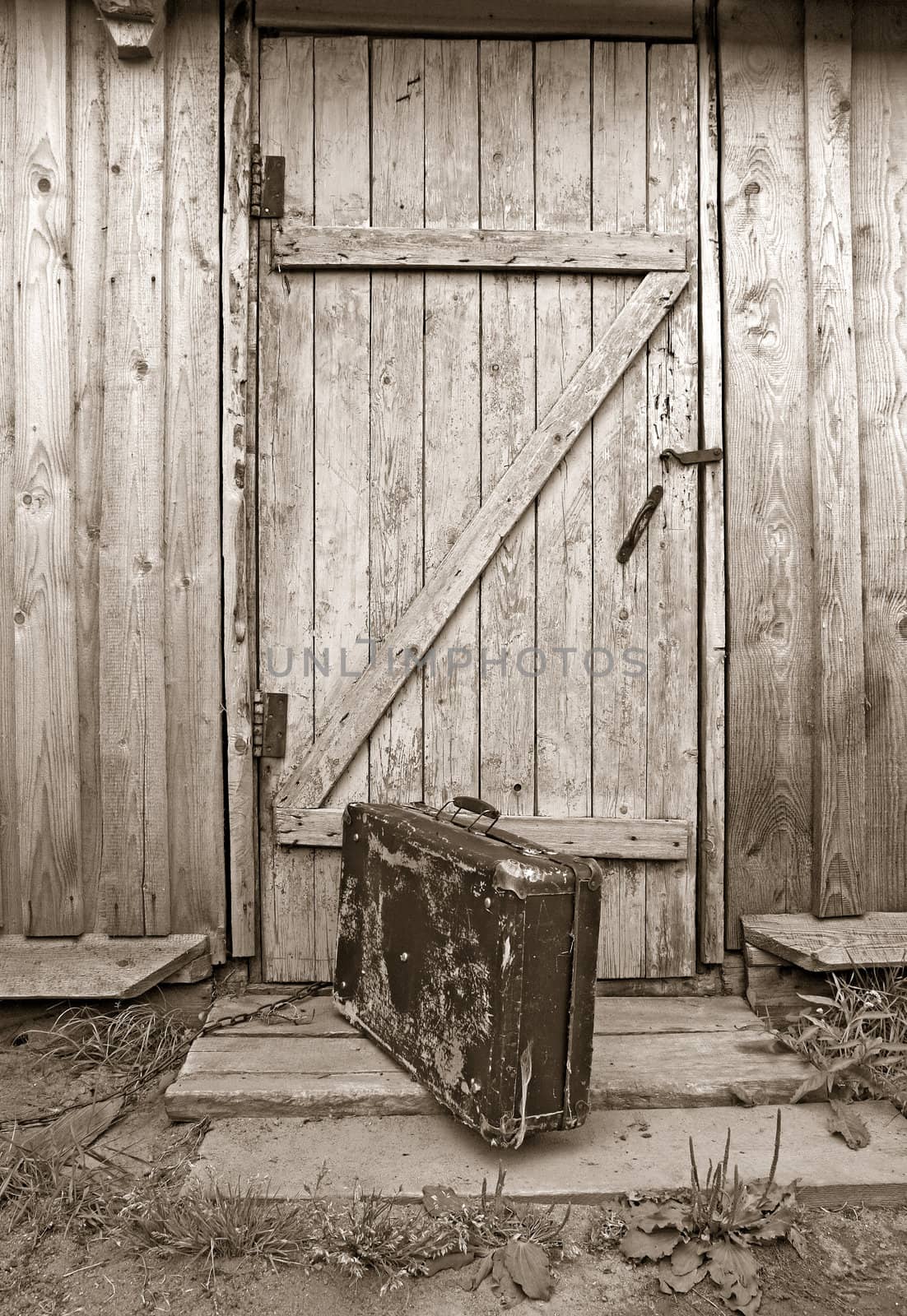 old valise near wooden door, sepia by basel101658
