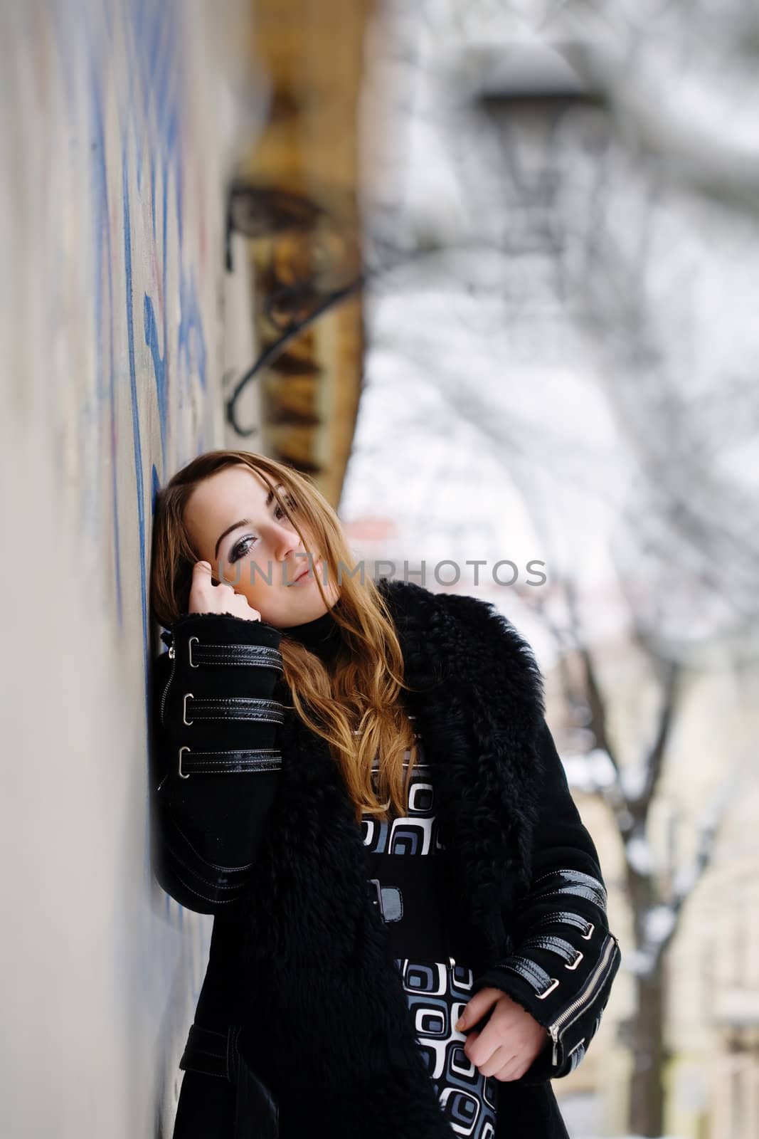Stock photo: an image of a beautiful girl standing near the wall