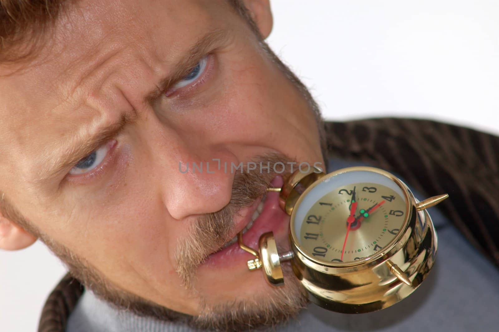 A man keeping an alarm clock in his teeth