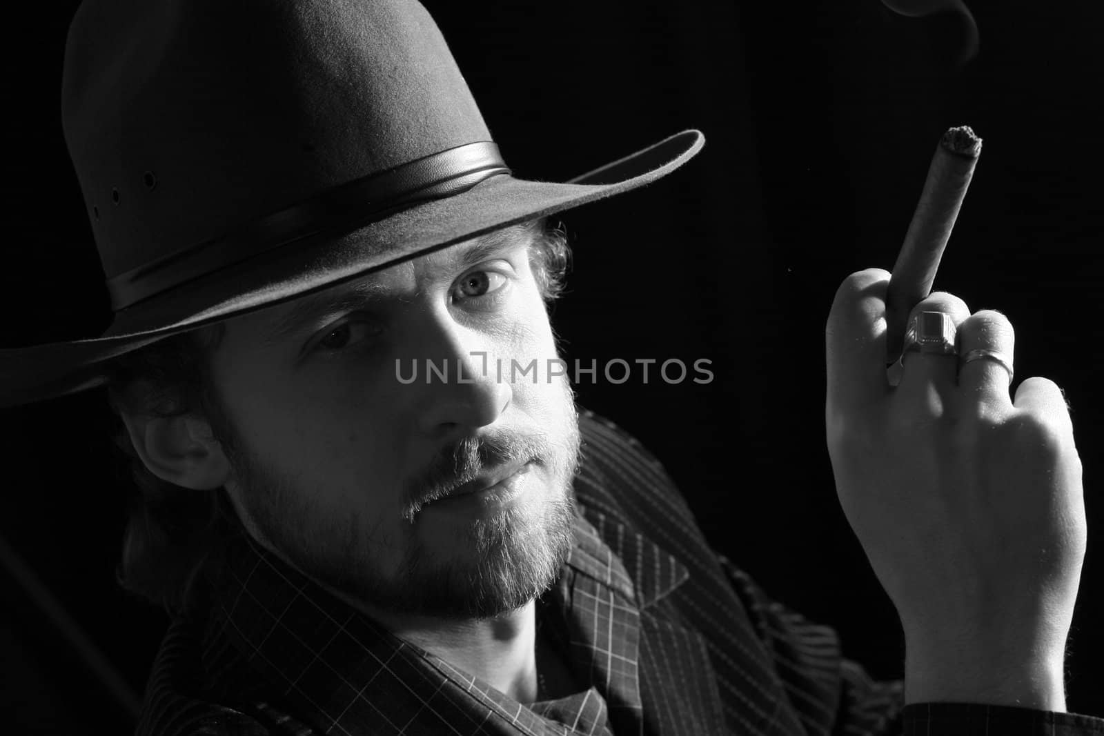 A man in hat keeping a cigar in his fingers