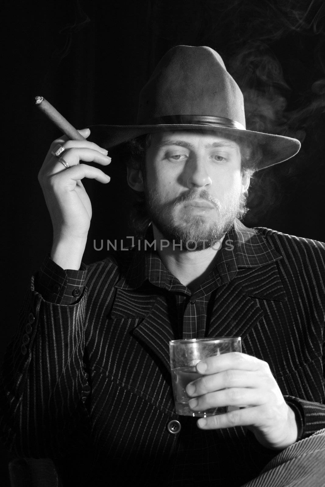 An image of a bearded man with cigar and glass