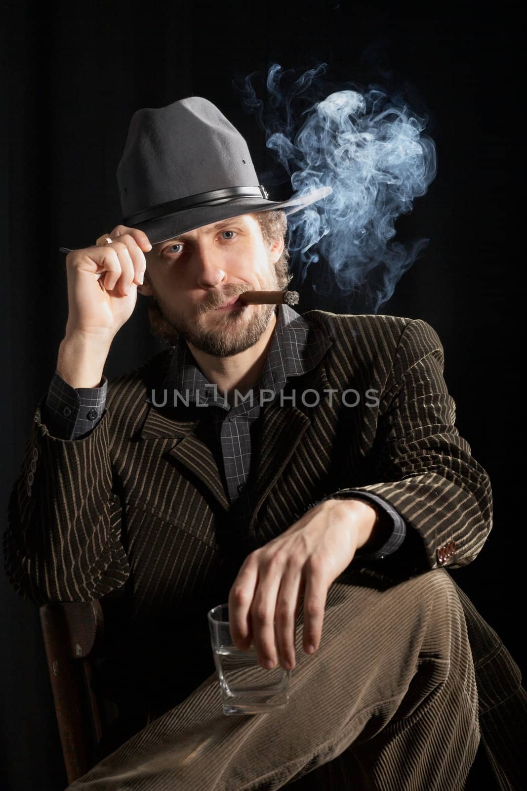 A handsome man in a grey hat  with a glass  and cigar