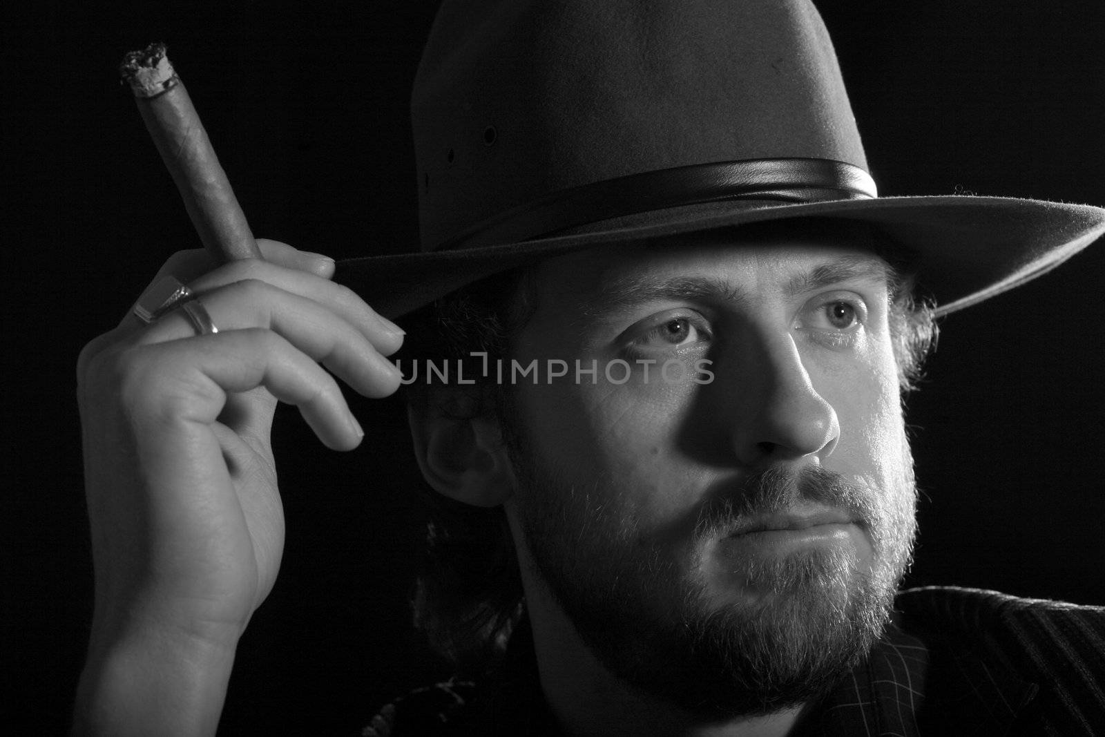 An image of bearded  man with cigar in dark room