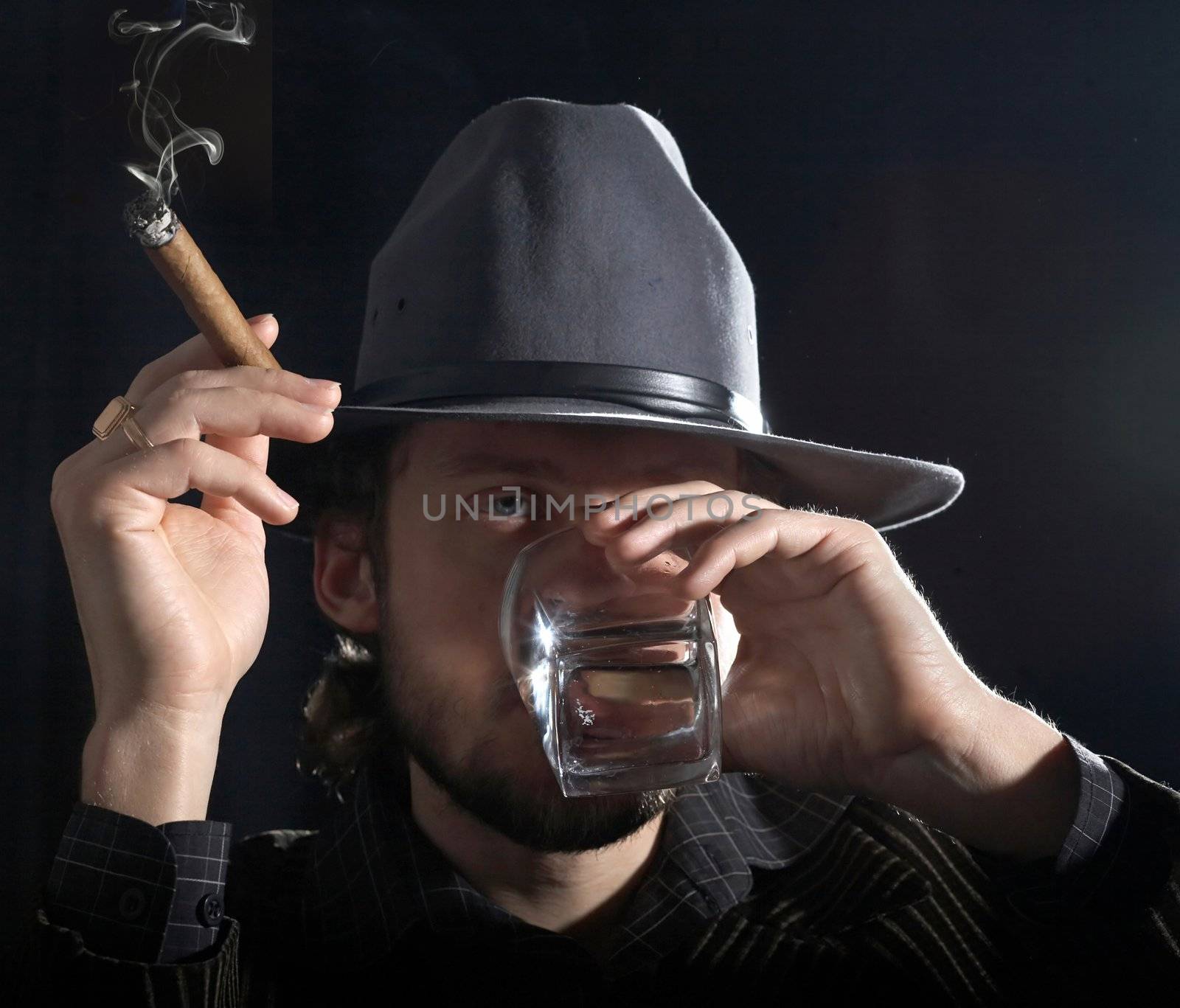 An image of a bearded man with cigar and glass