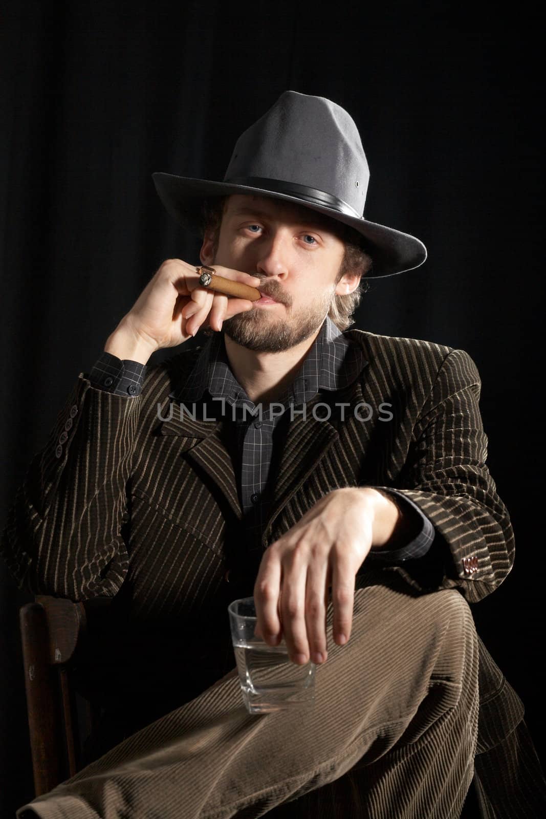 A young bearded man with a glass of whiskey and cigar