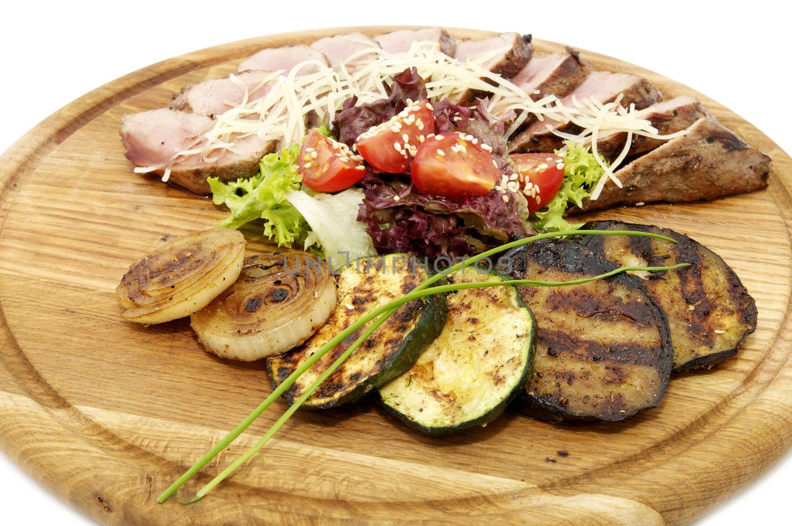 grilled vegetables and meat on a wooden platter