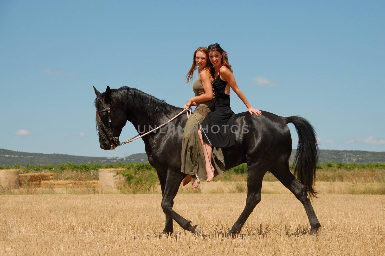 two friends are horseback riding their black stallion