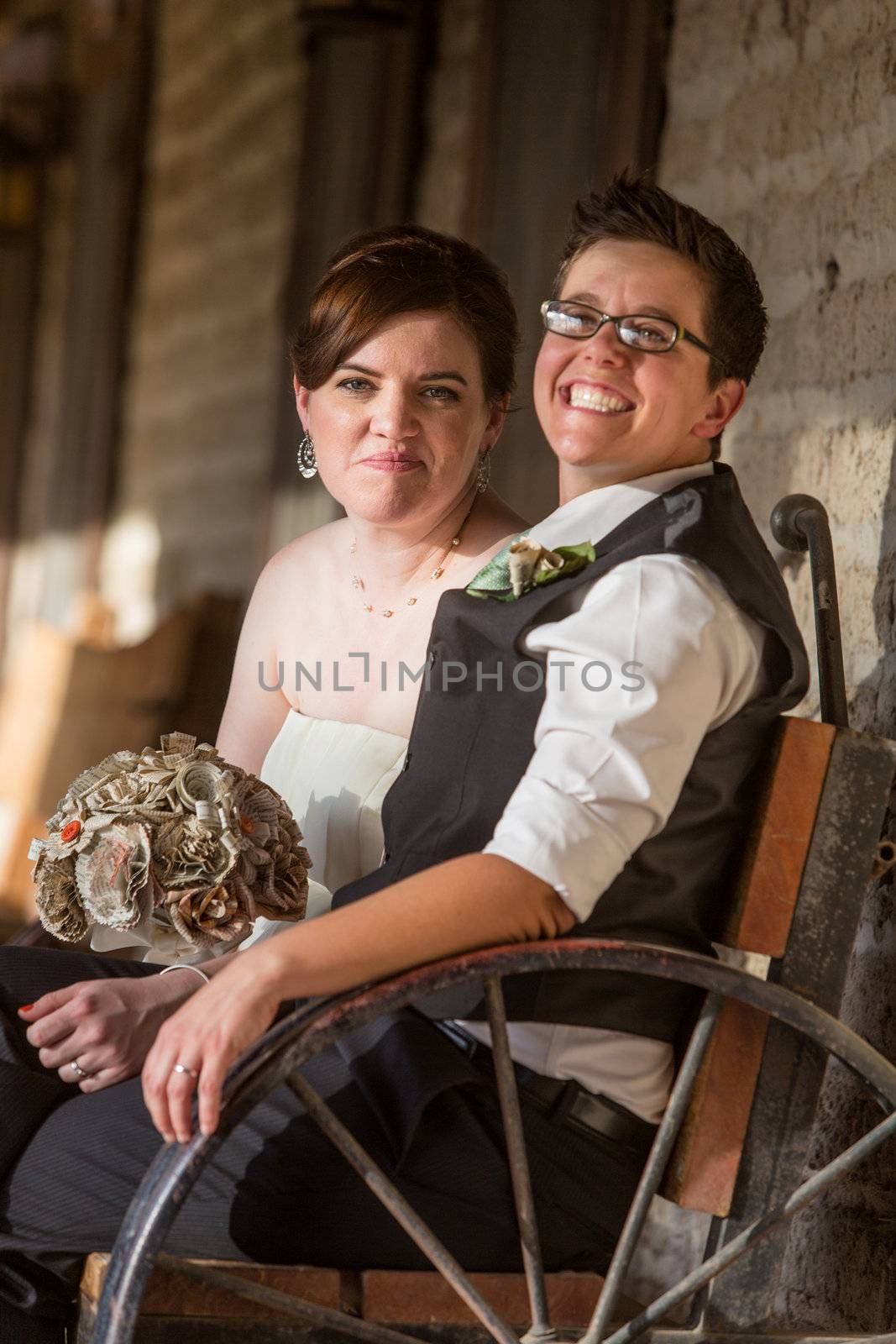 Smiling newlywed gay couple sitting on antique bench
