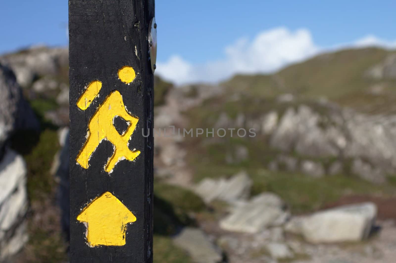 Yellow trekking sign on a wooden pole