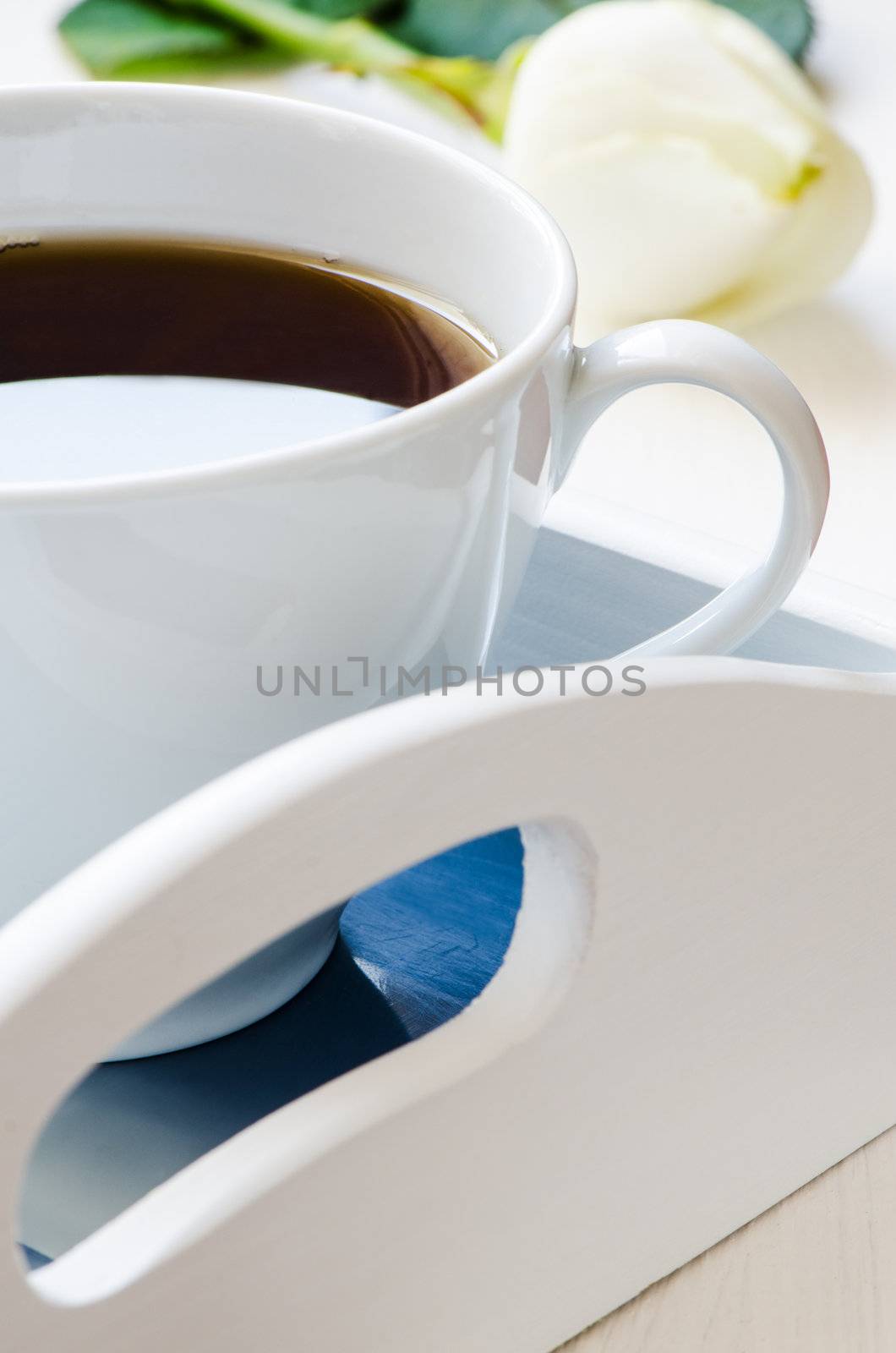 Cup of coffee on a tray with flower on background