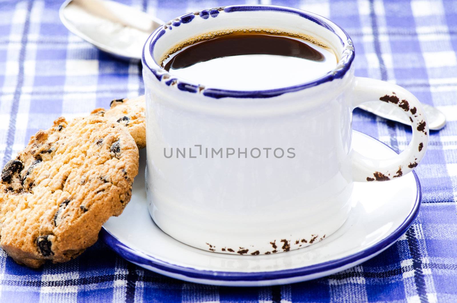 Cup of coffee cookies and teaspoon on blue cloth