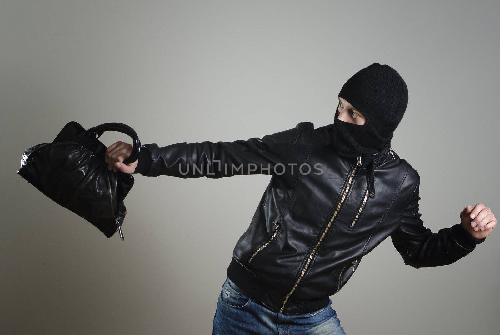 Portrait of running male burglar with a handbag.
