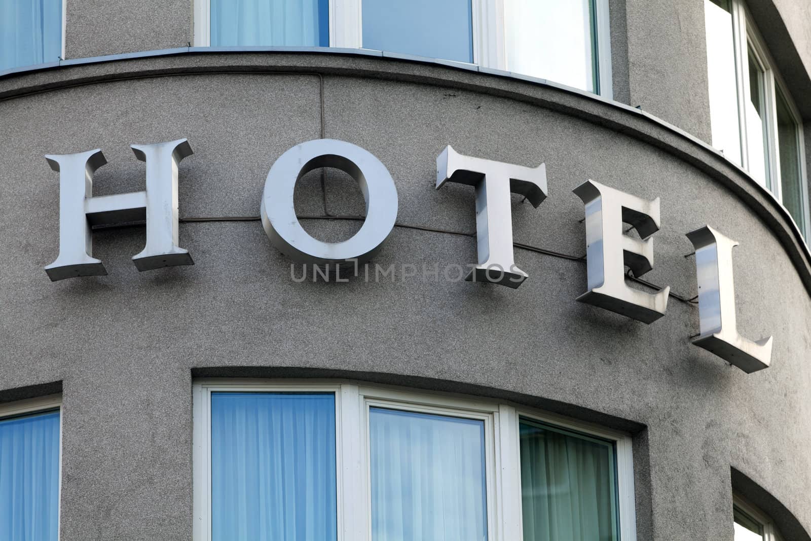 Hotel sign in exterior view on a rounded front of building by Portokalis