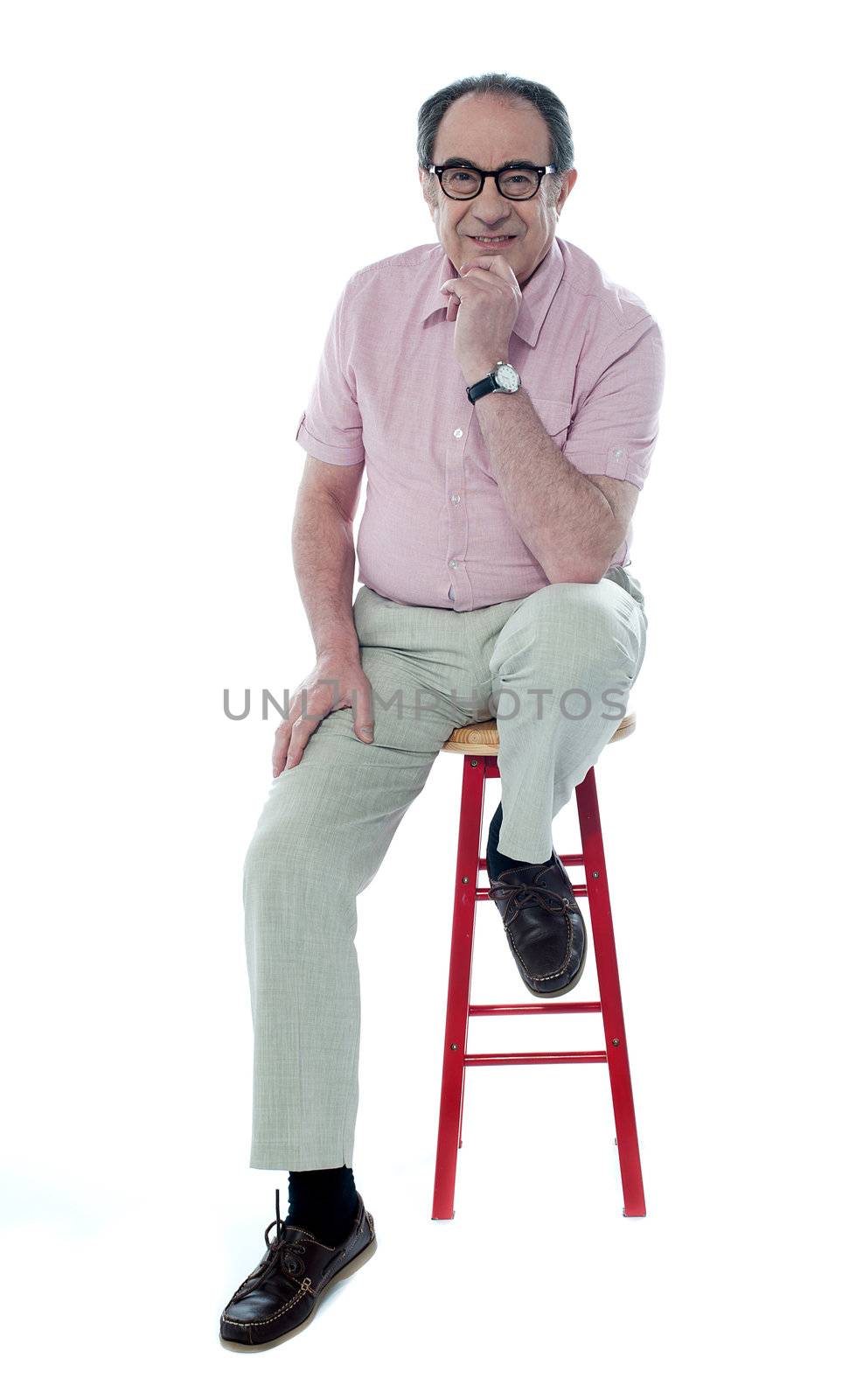 Confident senior man resting on stool by stockyimages