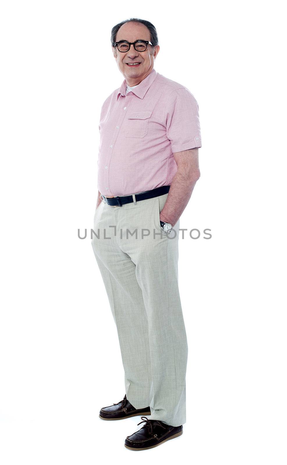 Senior man standing with hands in pocket, smiling at camera