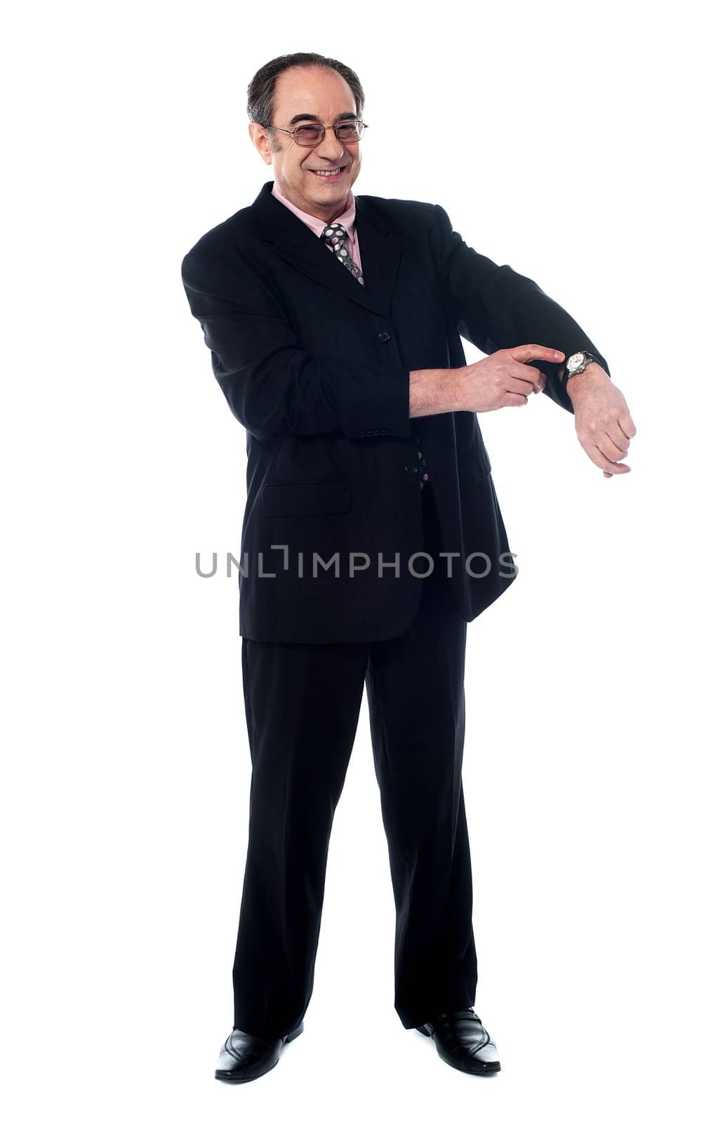 Senior businessman pointing towards wrist watch by stockyimages