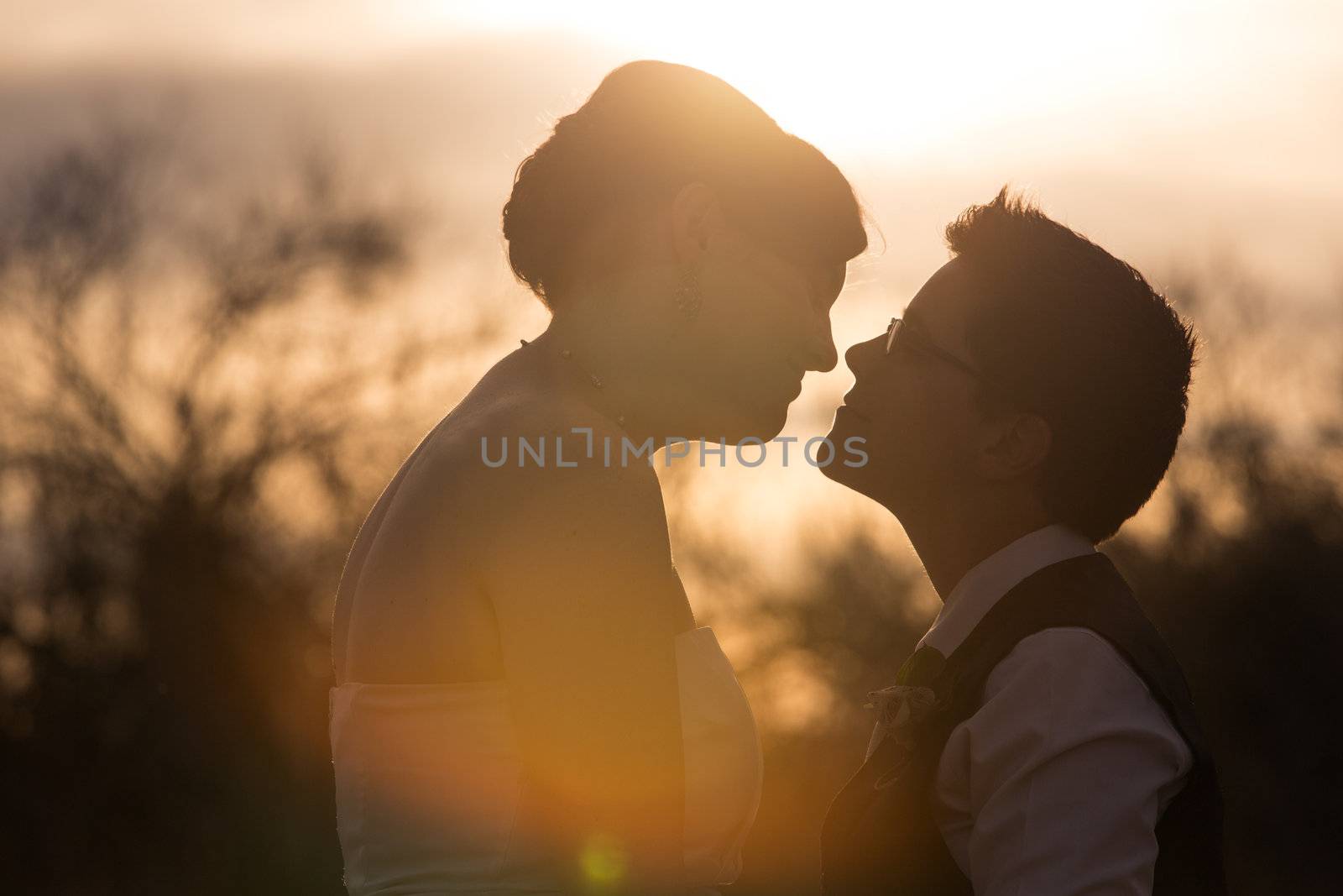 Bright sunset behind intimate lesbian couple outdoors