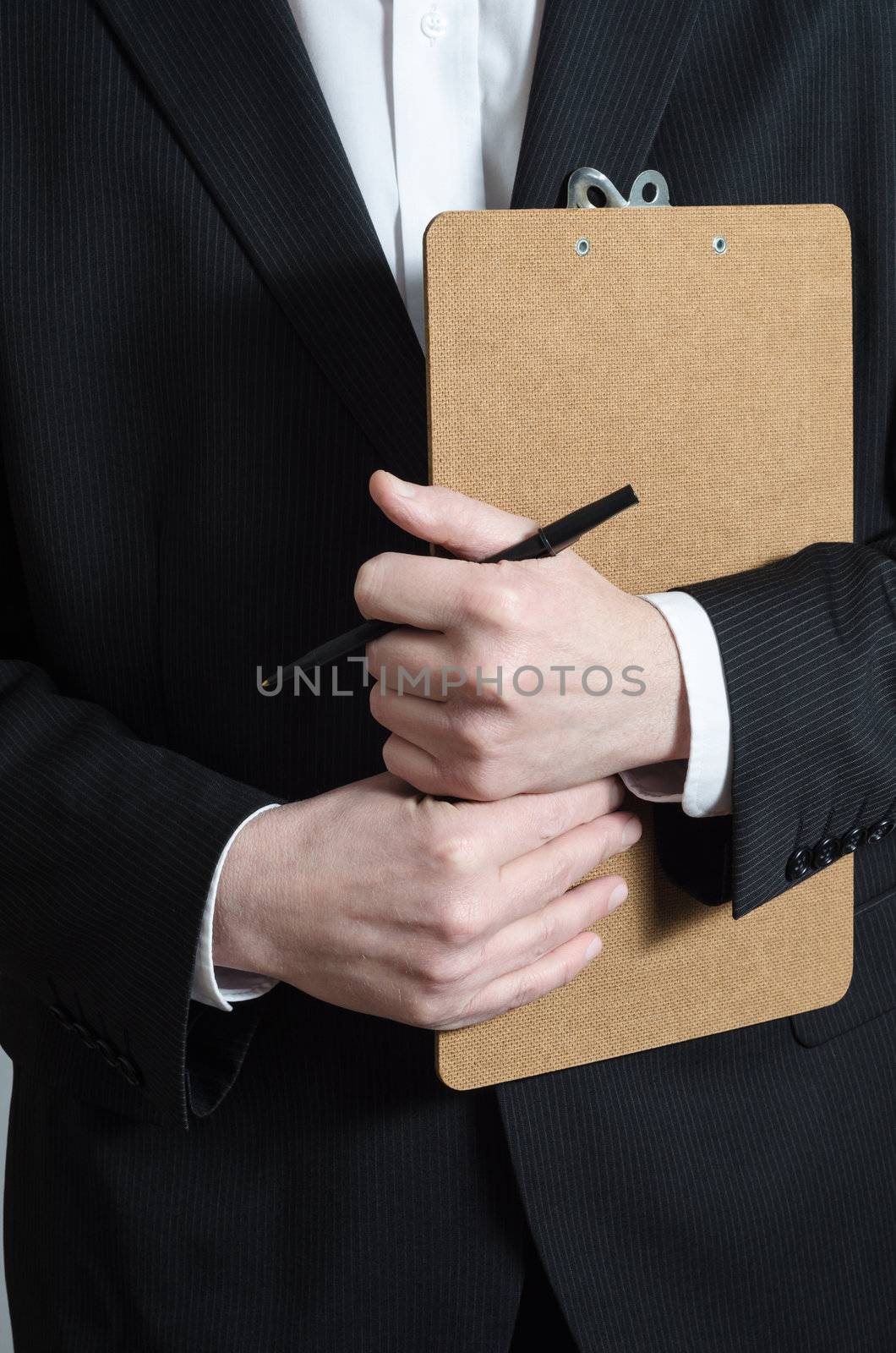 Close up crop shot of a male (torso) in a dark suit and white shirt, holding a clipboard and pen, waiting to collect research data or to confirm a booking or check his list.