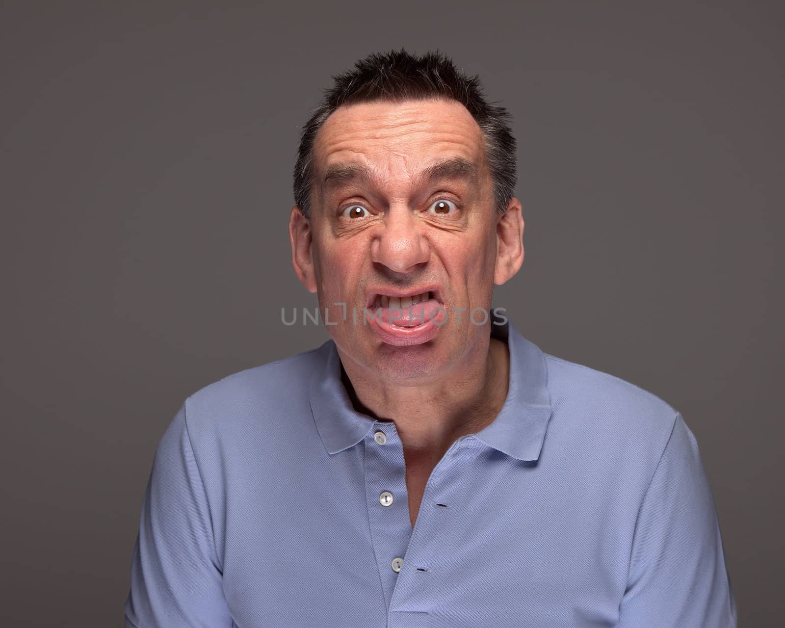 Handsome Middle Age Man Pulling Face Sticking Out Tongue on Grey Background