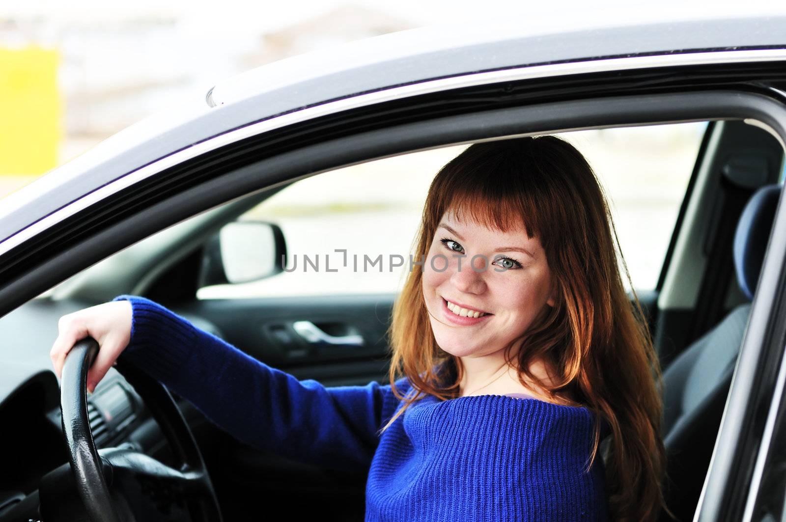 pretty redheaded happy teen girl driving a car 