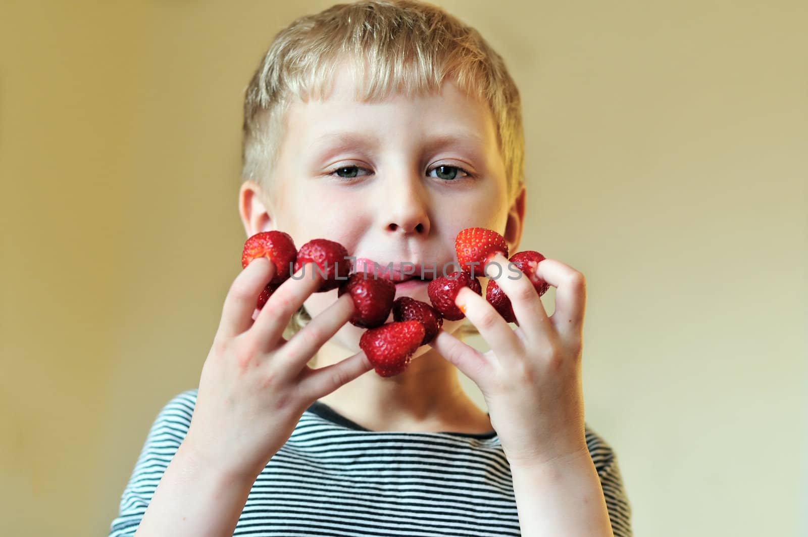 boy eating strawberry put on his fingers and smacking lips 