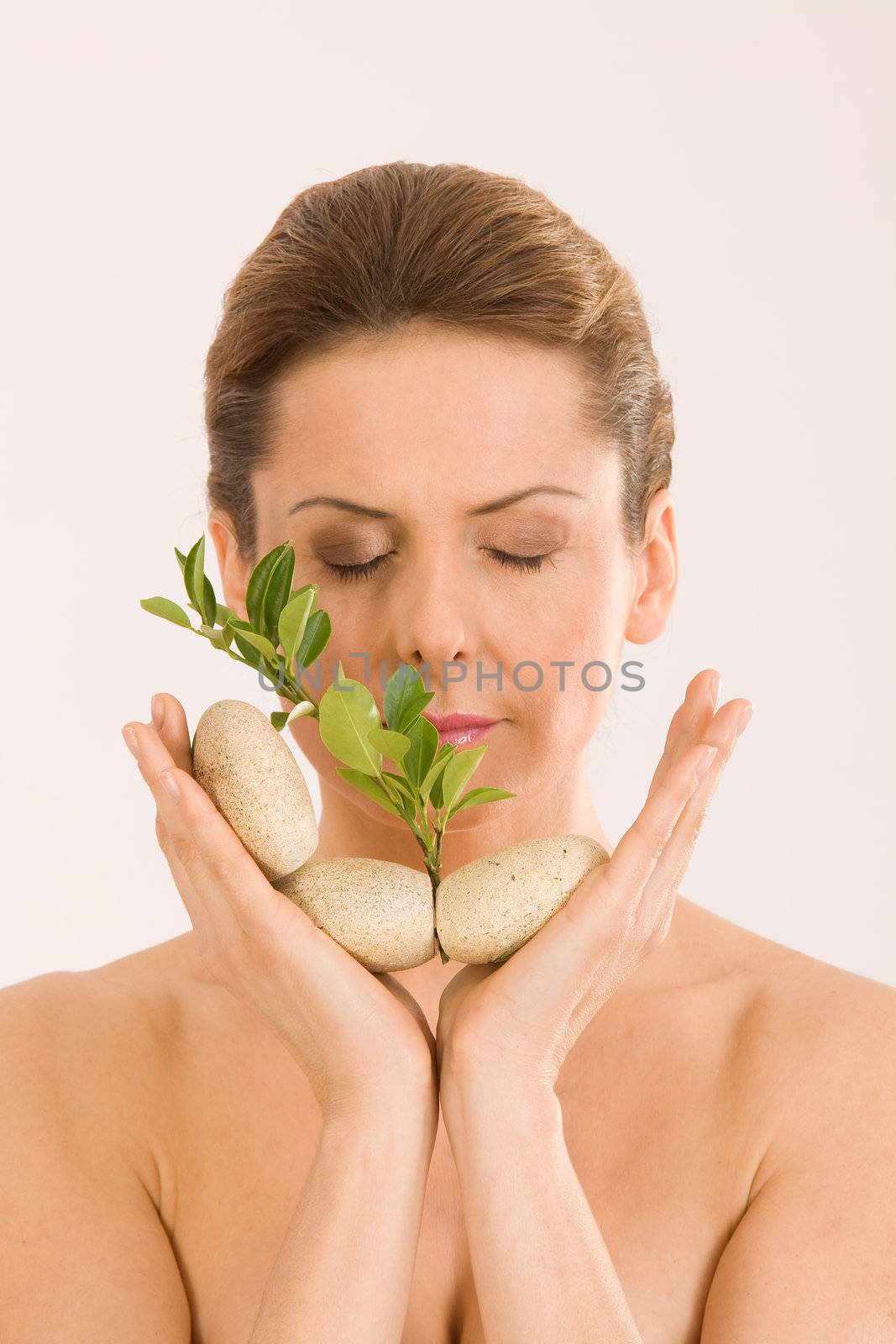 The woman relaxing with closed eyes, with pebbles and a herb in your hand