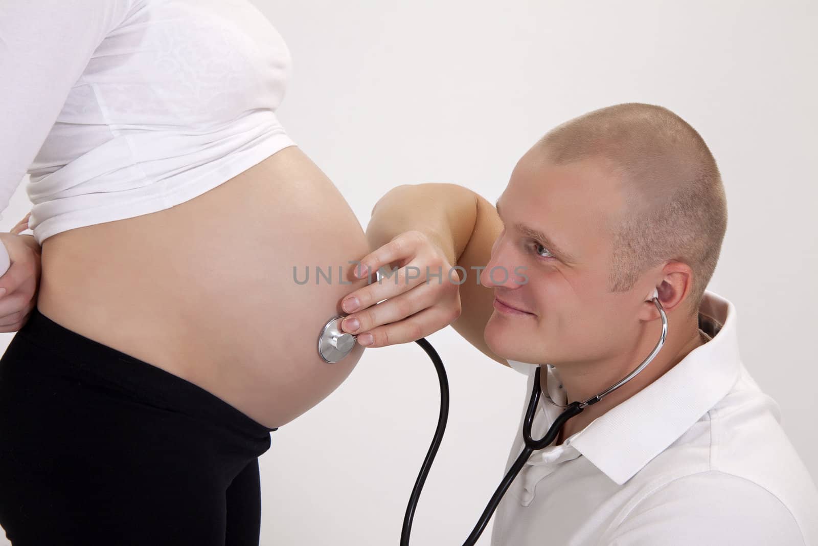 Pregnancy. Doctor with stethoscope listens to patient. by DianaLipkina