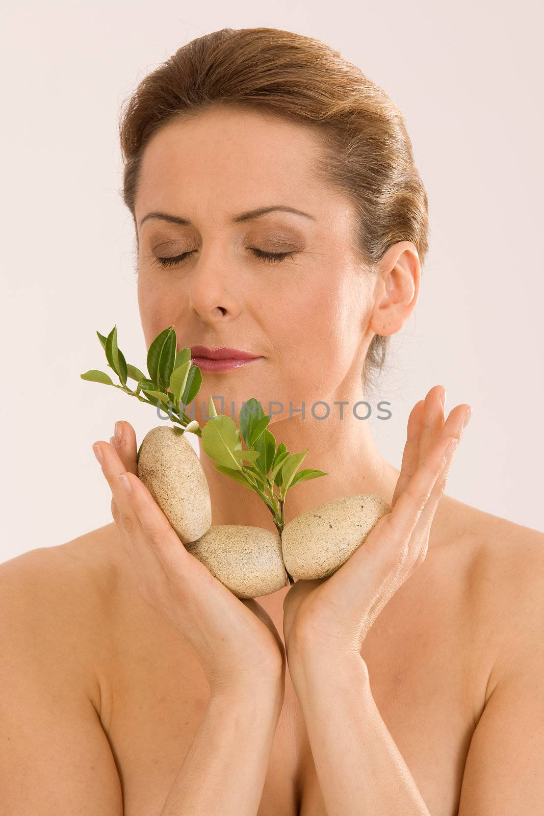 The woman relaxing with closed eyes, with pebbles and a herb in your hand