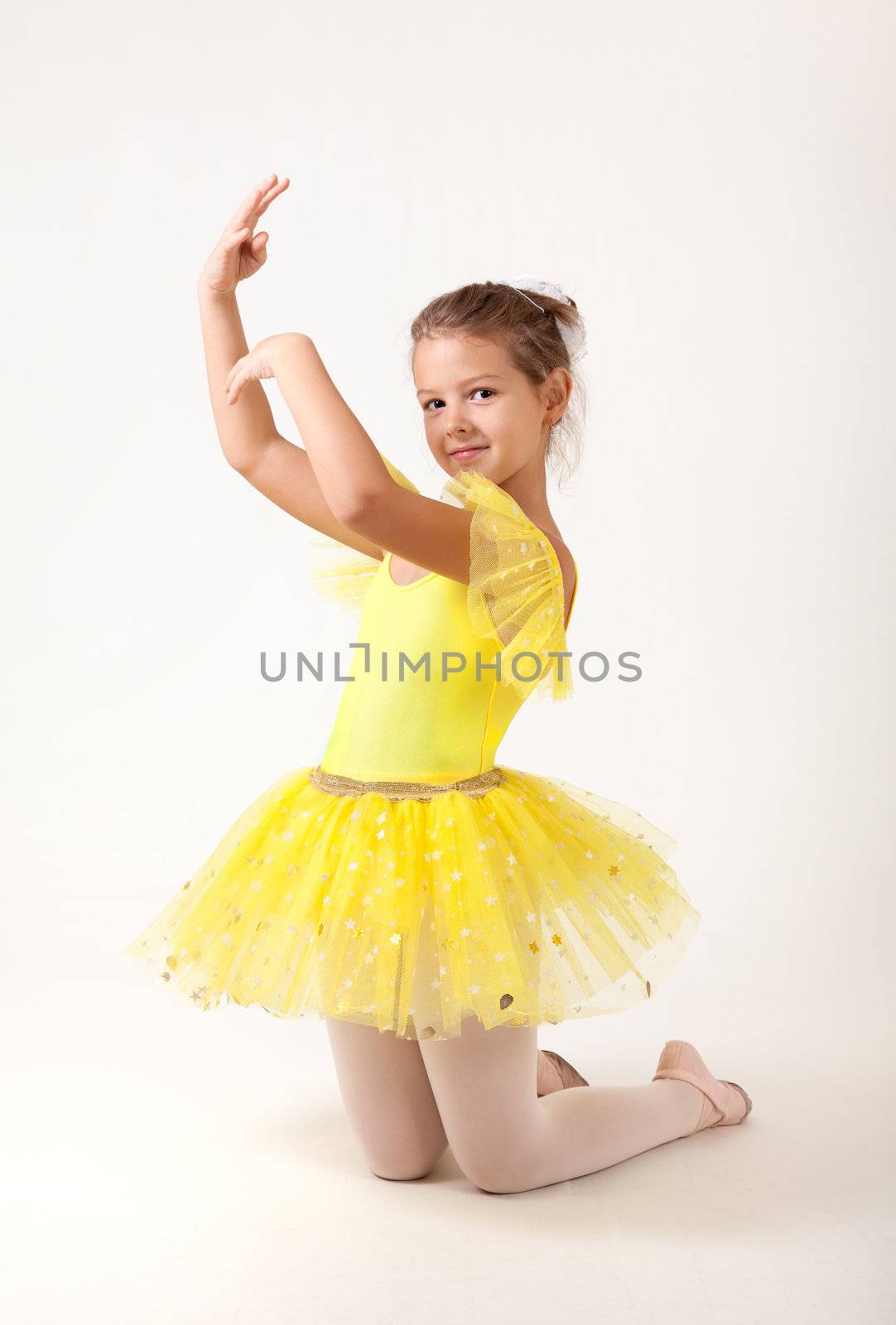 Cute little ballerina exercising, studio shot on white background 