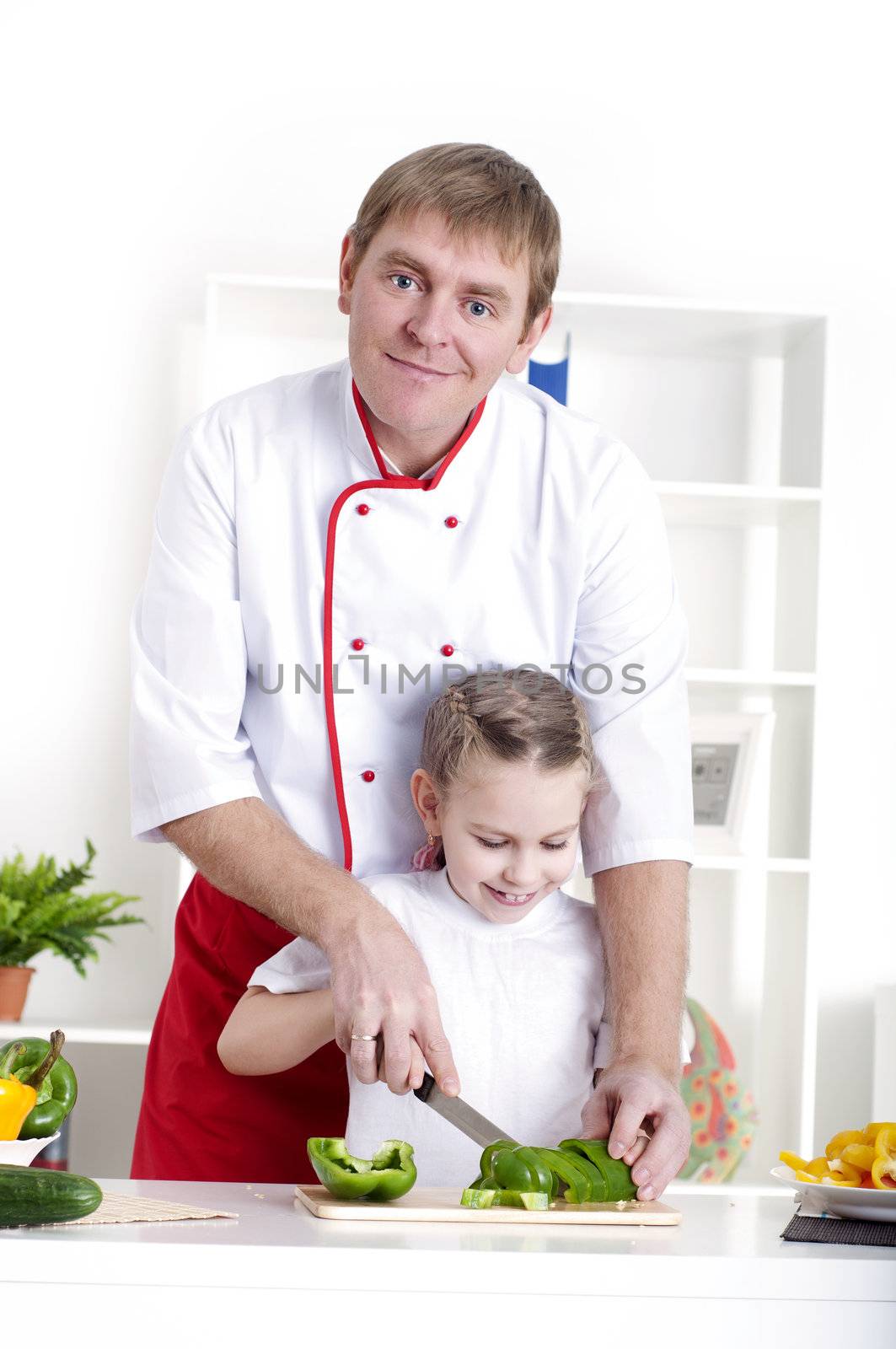 portrait of father and daughter cooking salad together in the kitchen