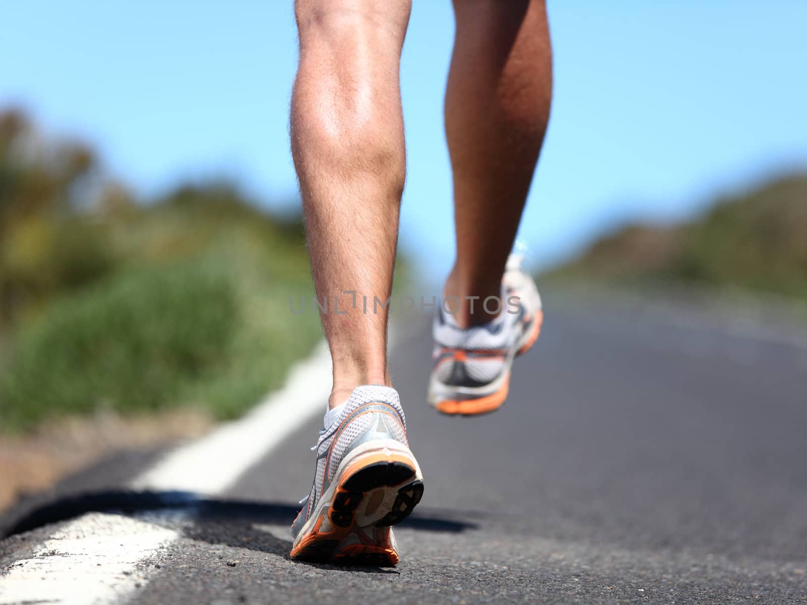 Running sport shoes on runner. Legs and running shoe closeup of man jogging outdoors on road.
