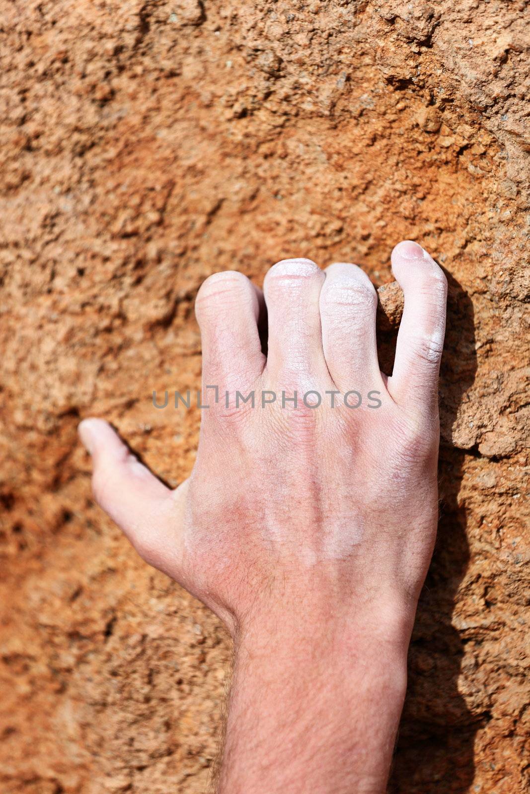 Climbing hand grip on rock. Male hand with chalk powder on rocks.