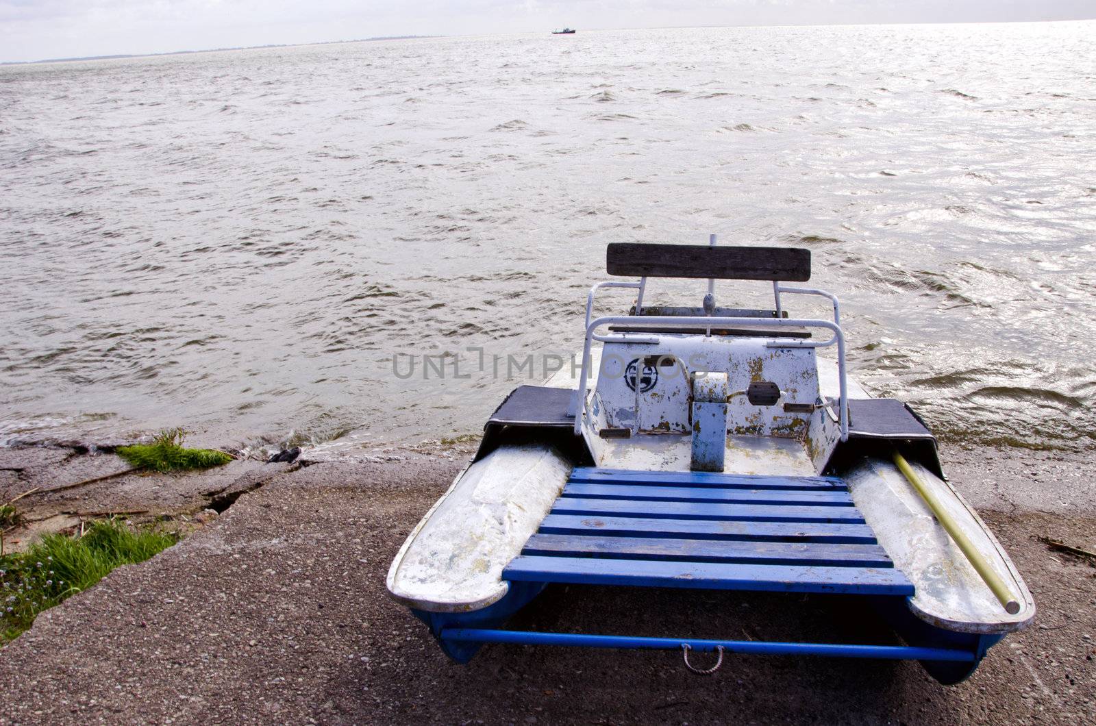 water bike catamaran on lake concrete pier. ship in distance. waving water.