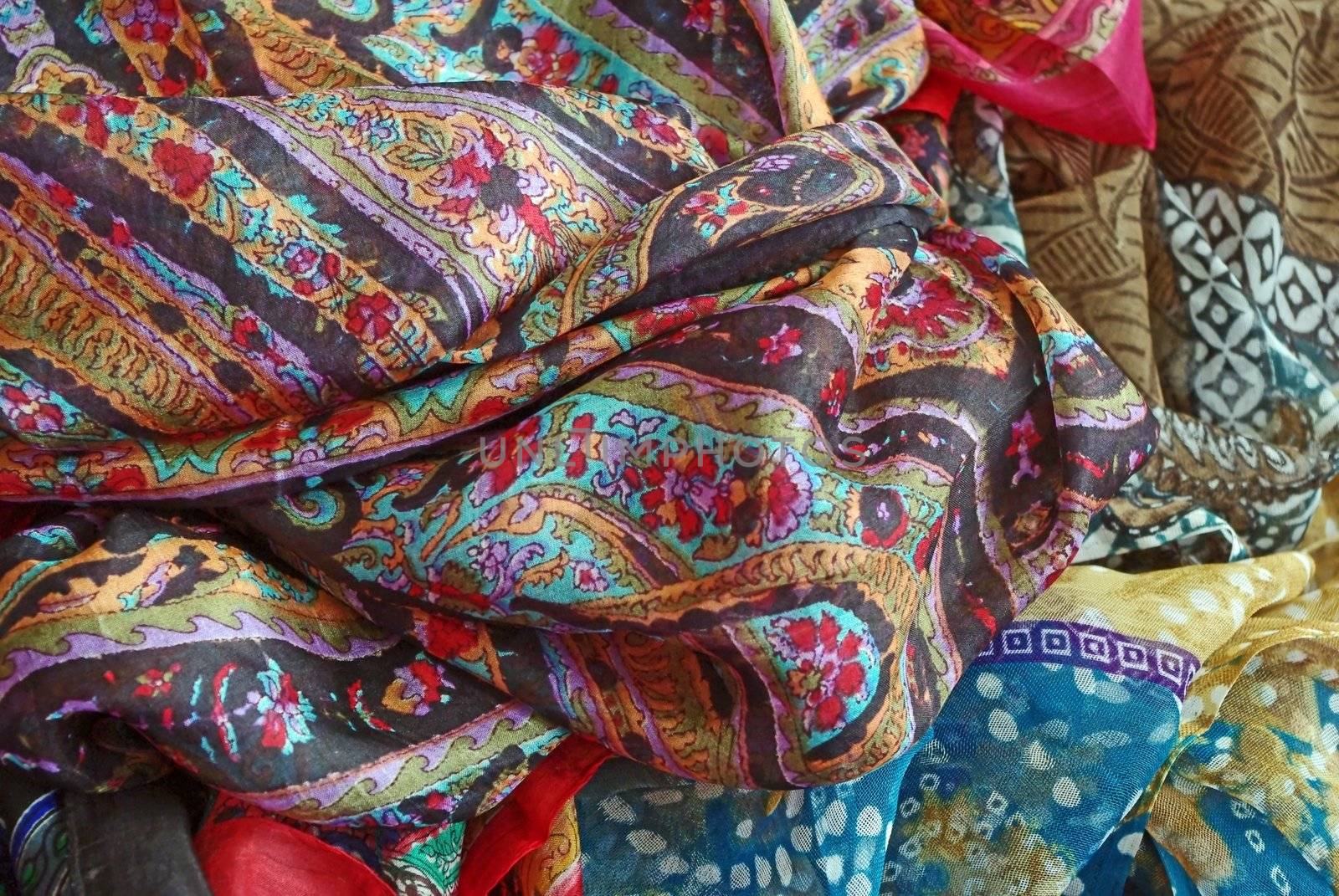Pile of folded colour fabrics and shawls (scarfs) at the market