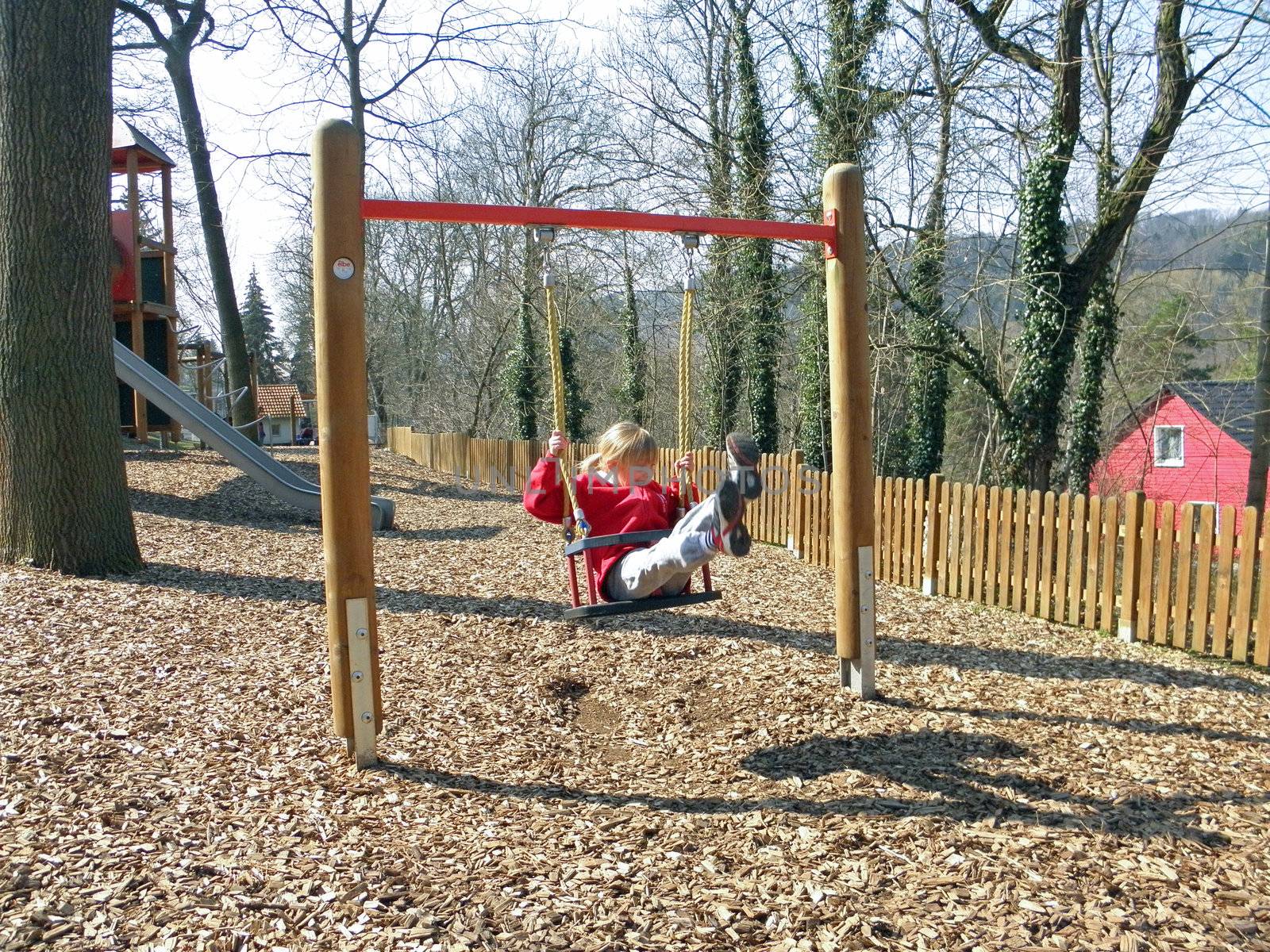 Photo of a blonde girl who plays on a playground.