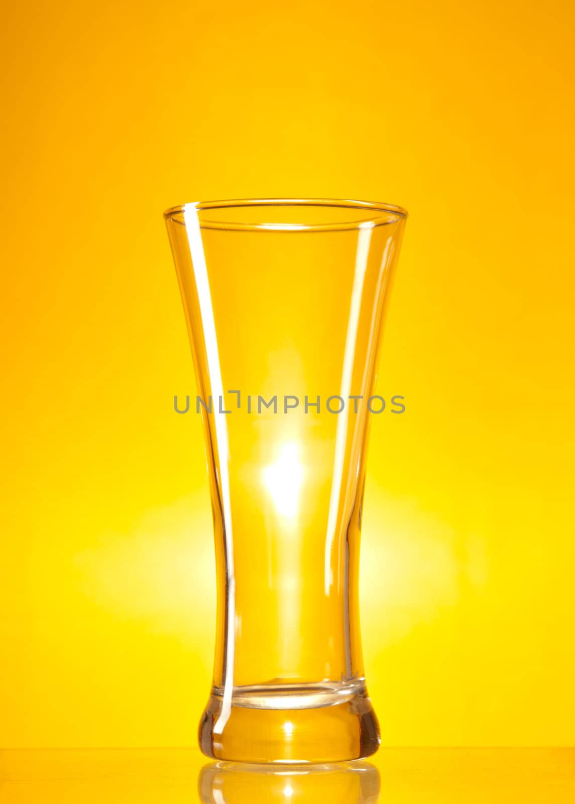 Empty beer glass over yellow background 