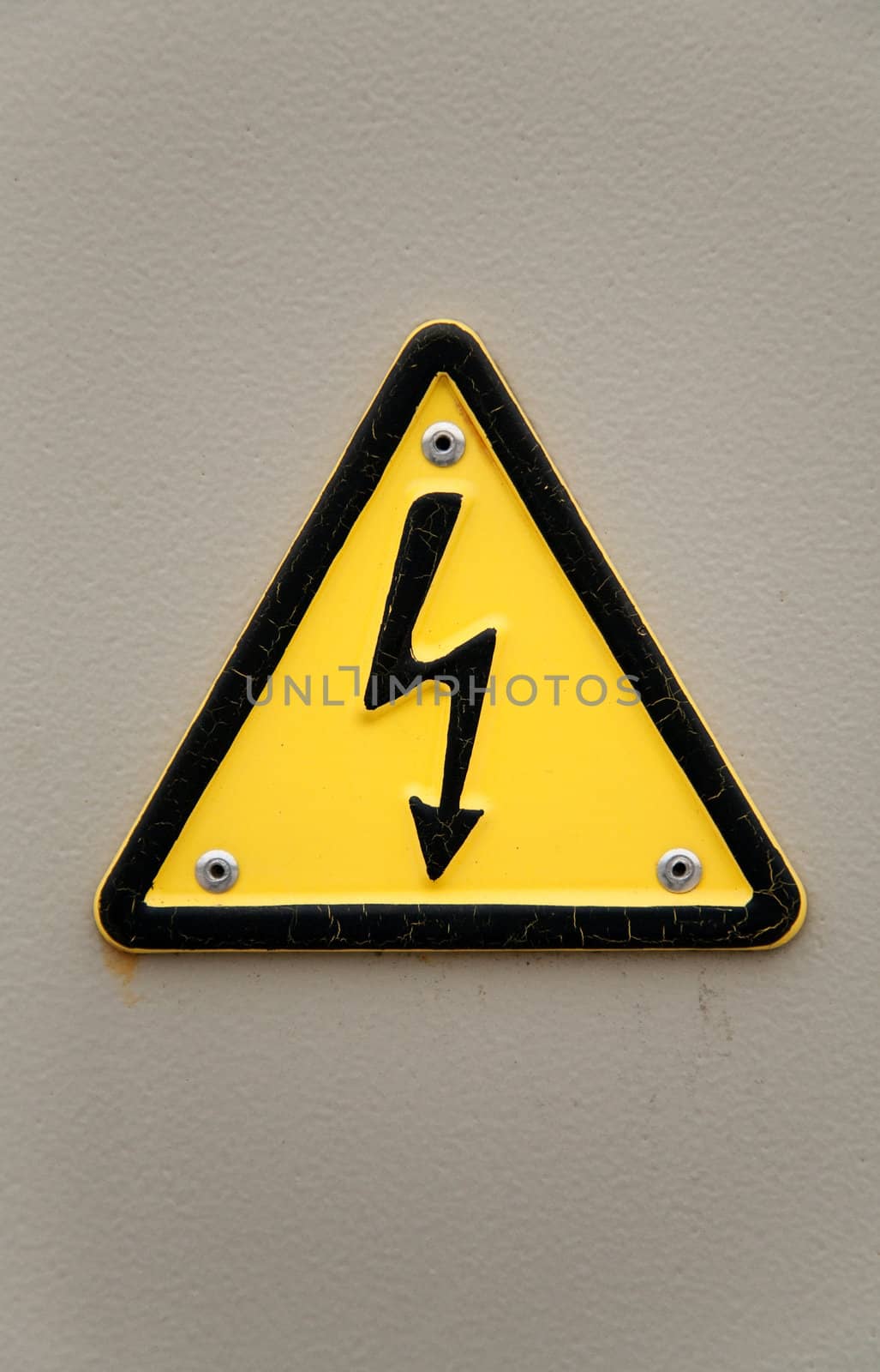 Grungy high voltage sign over gray wall background 