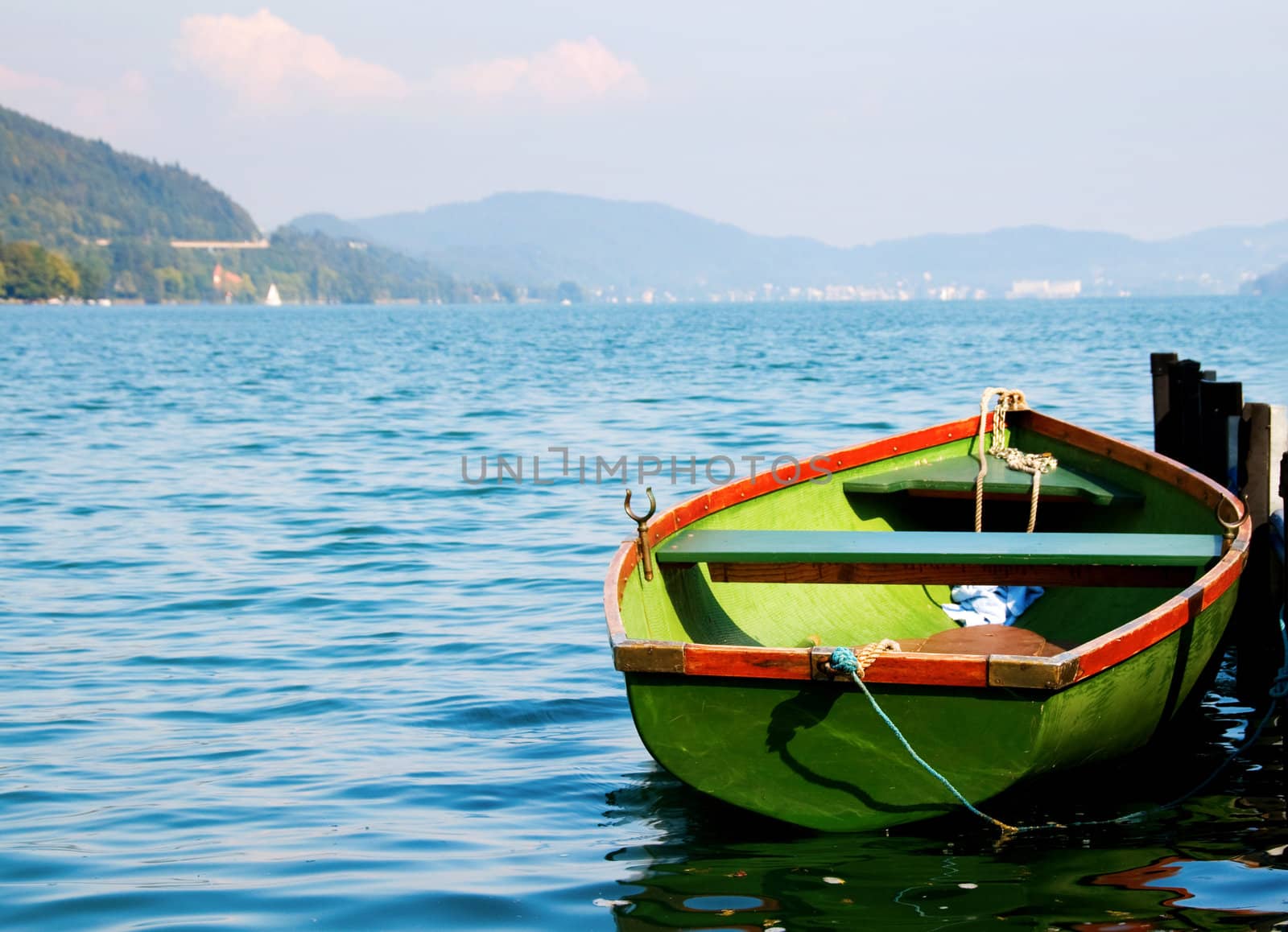 Green boat on water with mountains on background by iryna_rasko