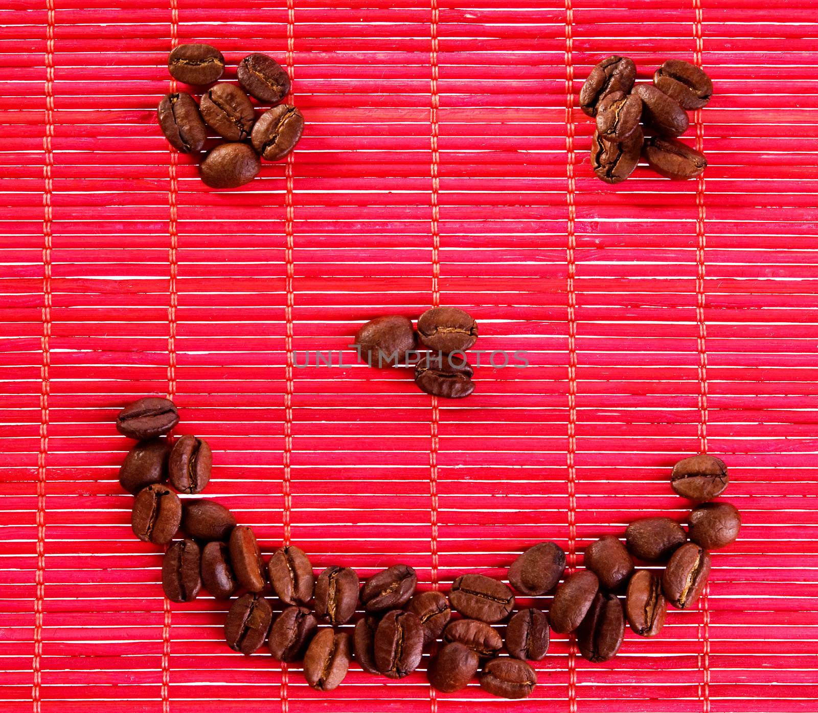 Roasted coffee beans placed in shape of smile on a bamboo mat