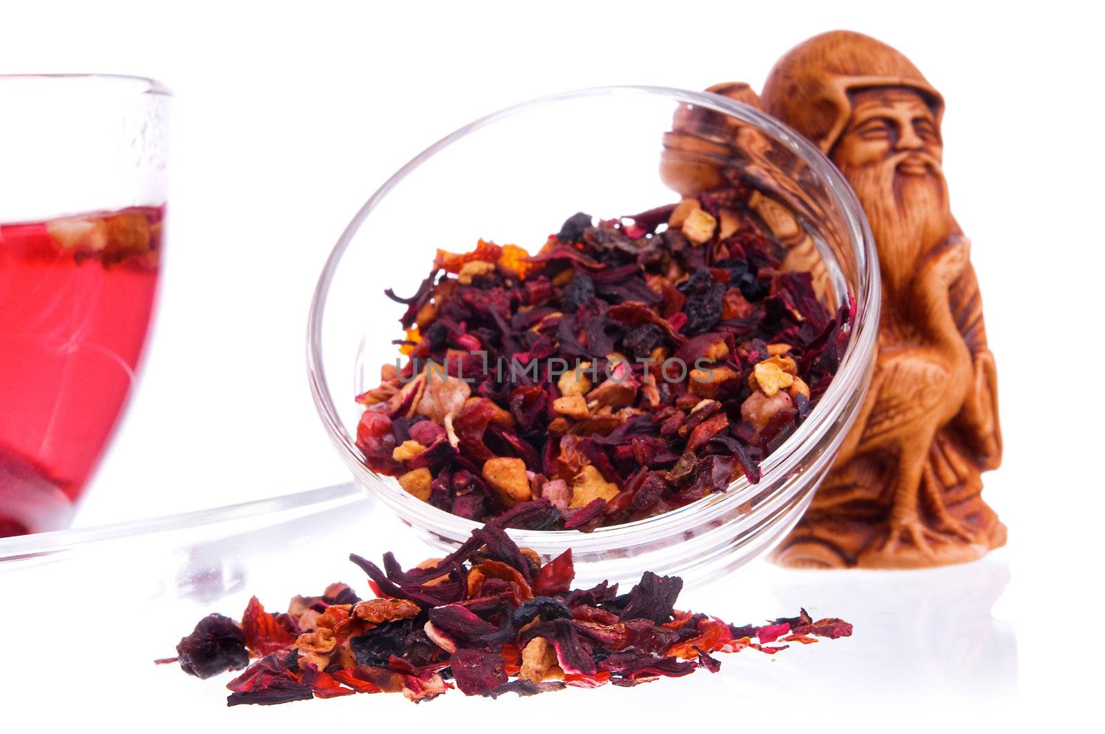 Healthy dry fruit tea in a transparent saucers and idol of prosperity statuette on background out of focus. Shallow depth-of-field, focus on tea heap.