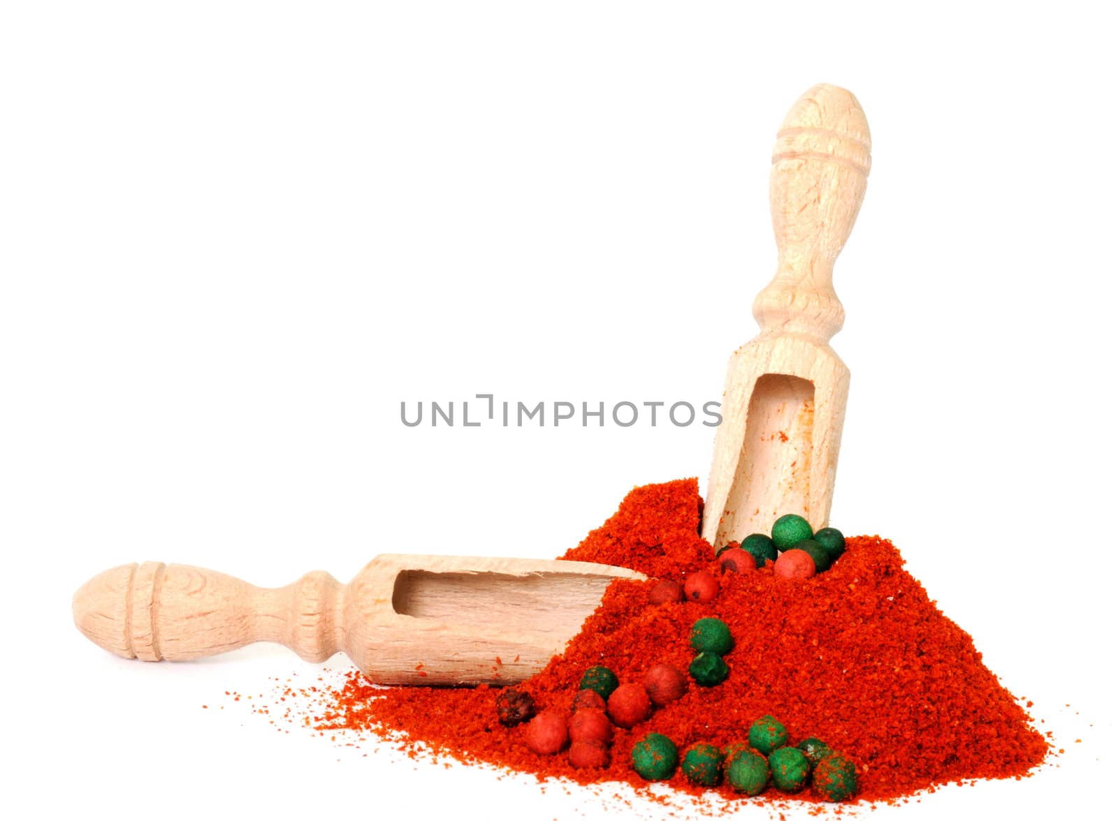 Two wooden scoops in heap of powder pepper with red and green peppercorns