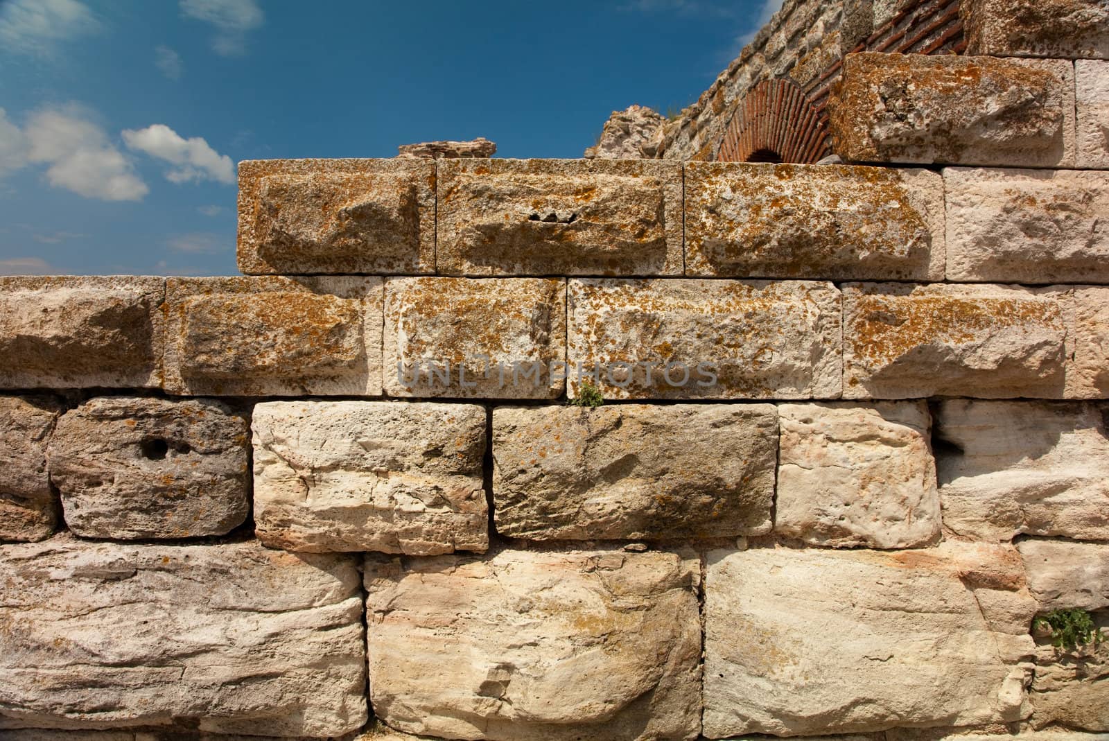 Ancient aged stone wall, blue sky background 