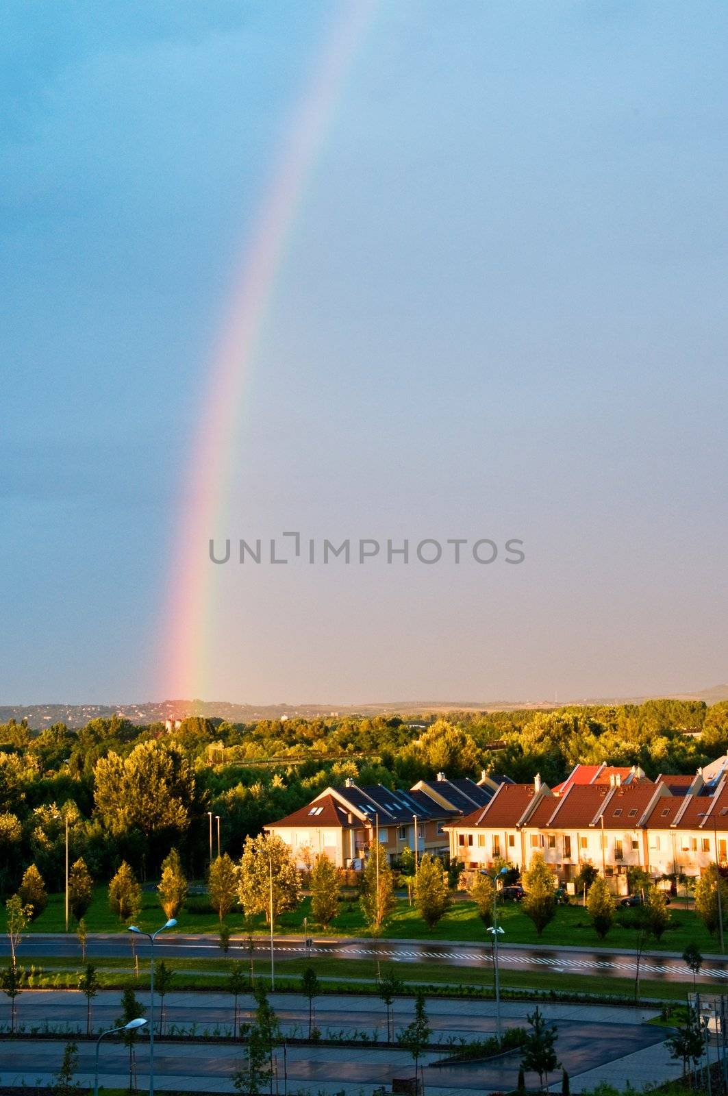 Rainbow at sunset under houses as a hope symbol