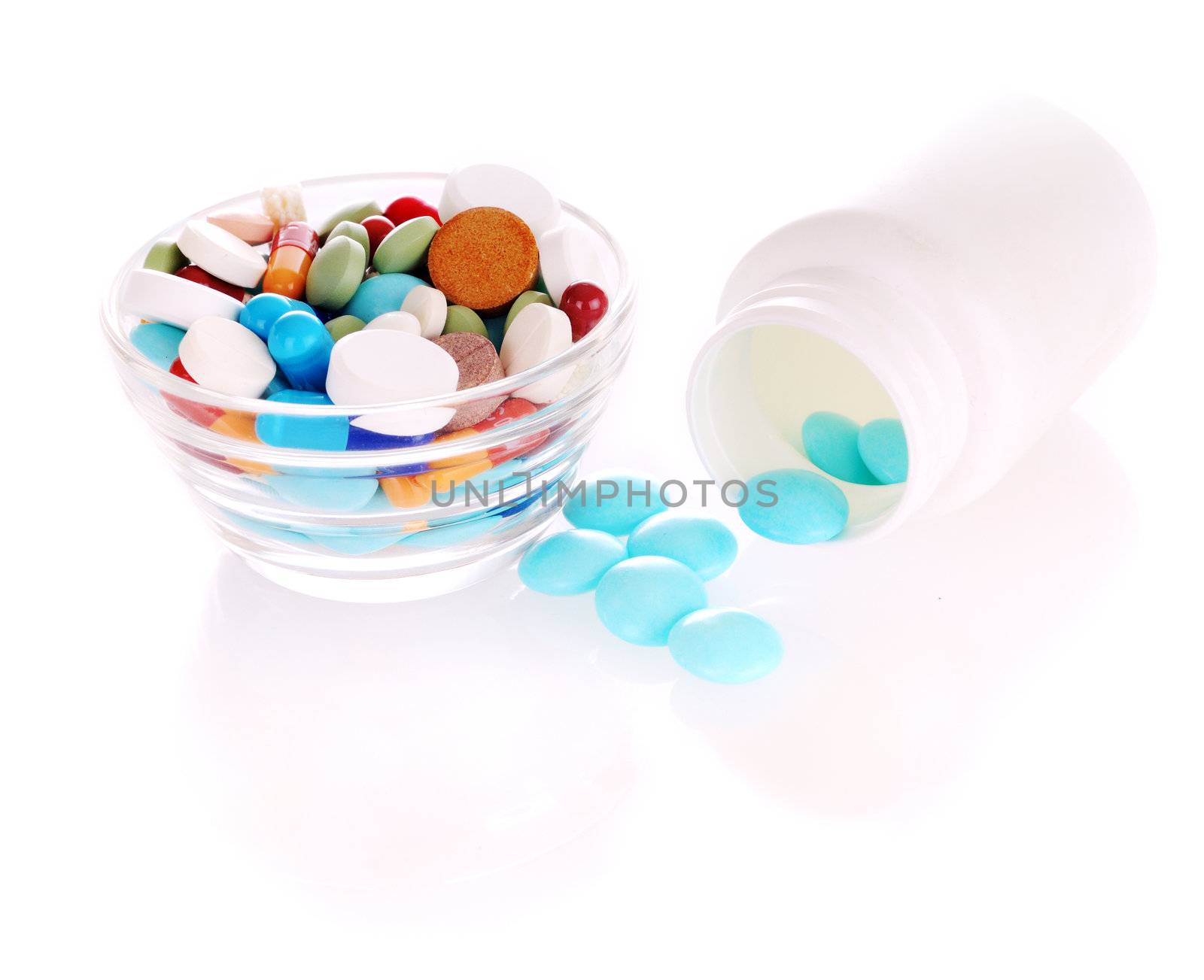 White bottle with blue tablets and transparent saucer with many-colored pills