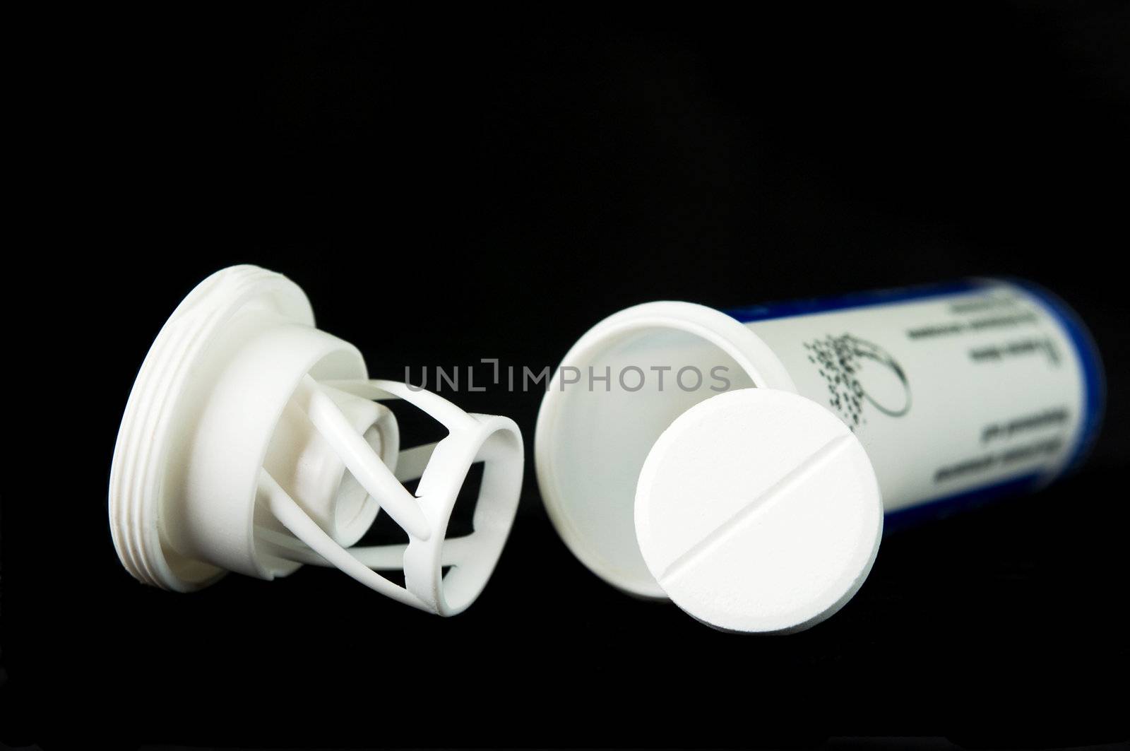White soluble tablet with bottle on black background