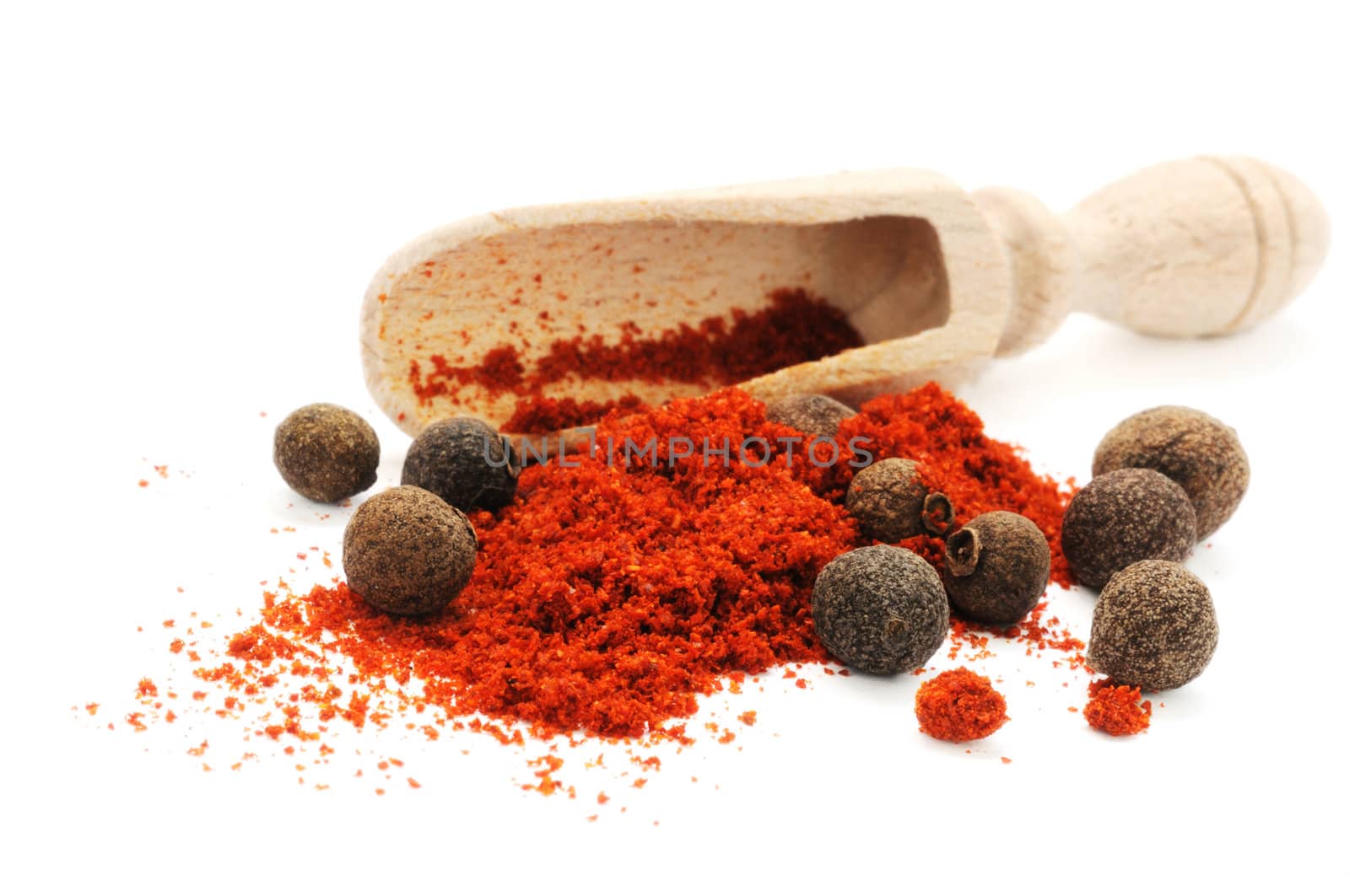 Wooden scoop in heap of pepper with peppercorns of sweet pepper