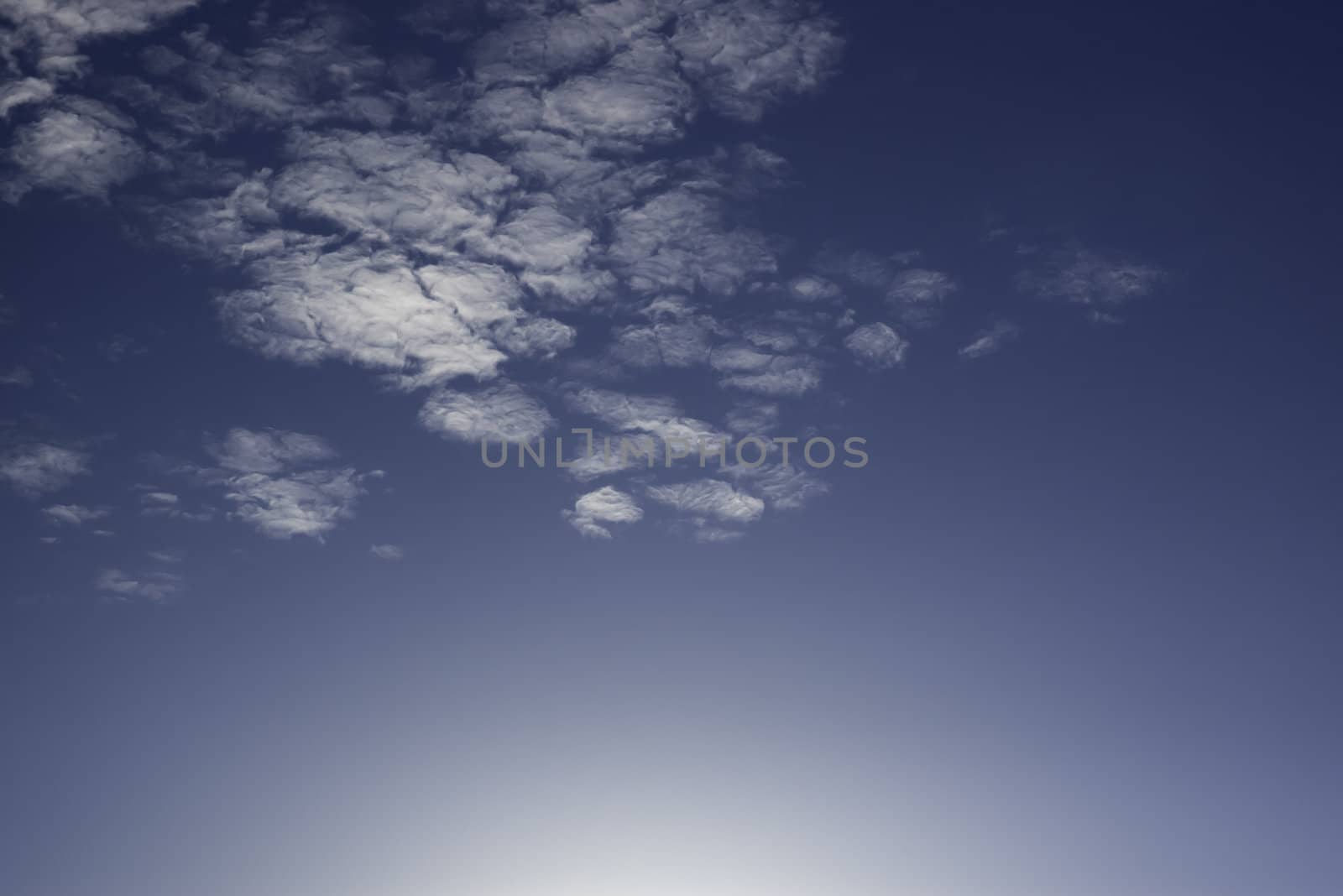 bright light low in sky with very light clouds and dark blue sky great for background