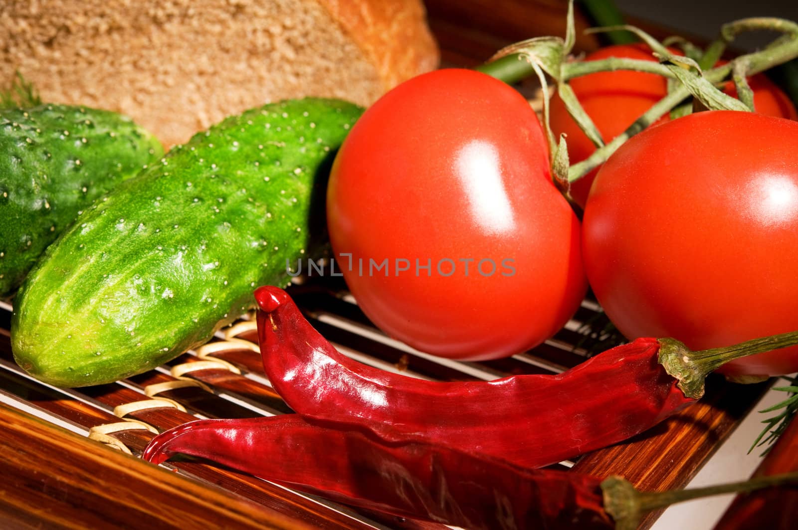Three tomatoes, two cucmber and peppers with bread on wooden tray