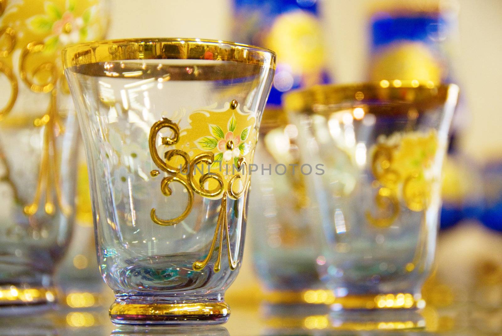 Transparent blue hand-made glass covered with gold drawing. Shallow depth-of-field