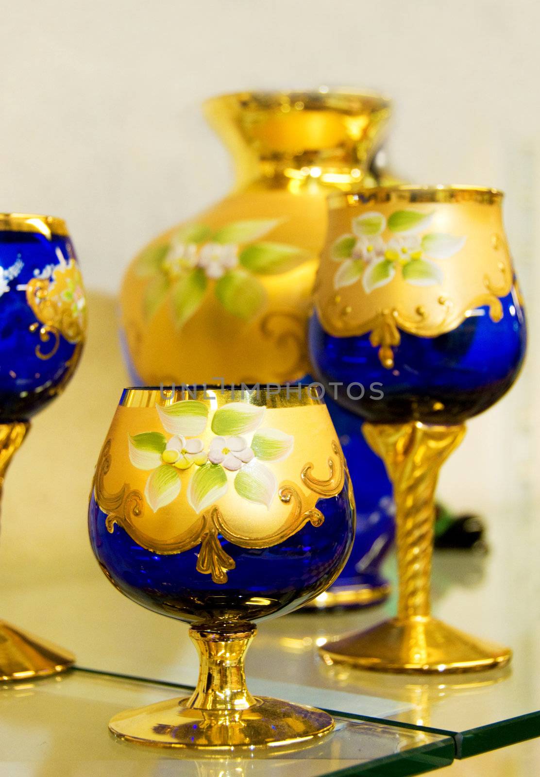 Transparent blue hand-made glass covered with gold drawing. Shallow depth-of-field